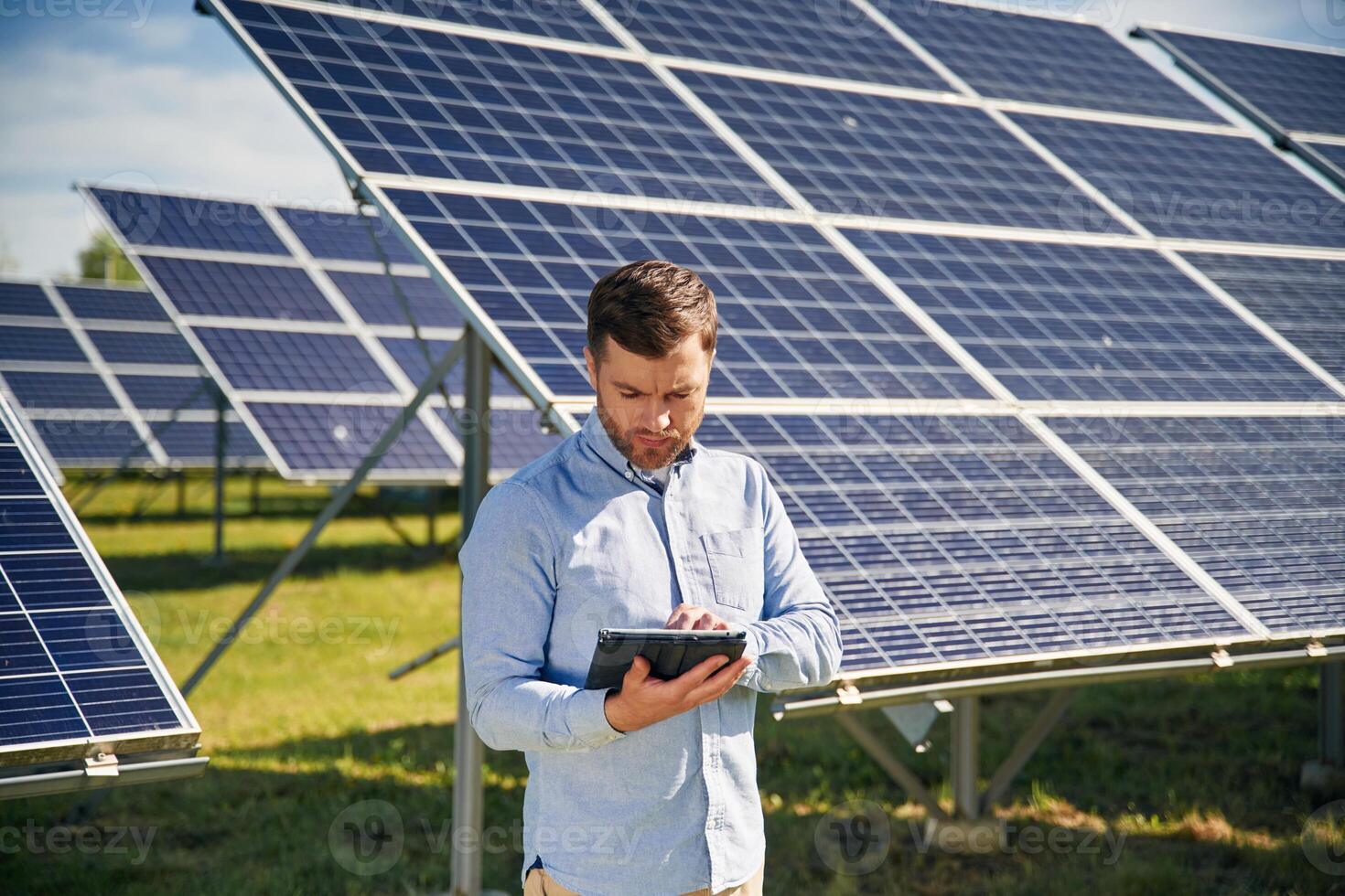 Digital tablet ,in ,,hand. Engineer with photovoltaic solar panels outdoors at daytime photo