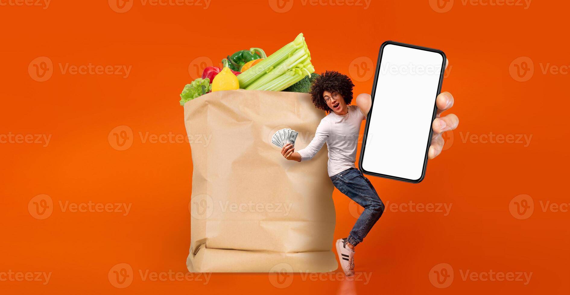 A customer with a cheerful expression stands next to a large paper bag filled with fresh groceries. photo