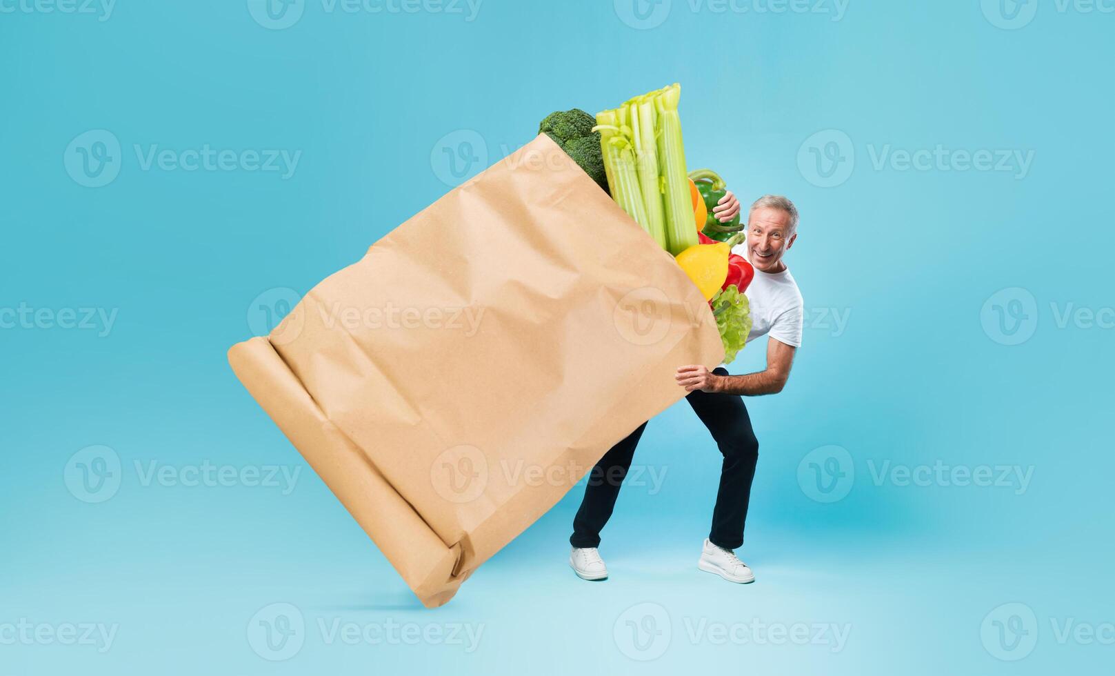 A customer holds a large paper bag overflowing with fresh vegetables and fruits while standing against a vibrant blue backdrop. This reflects a modern shopping experience during changing times. photo