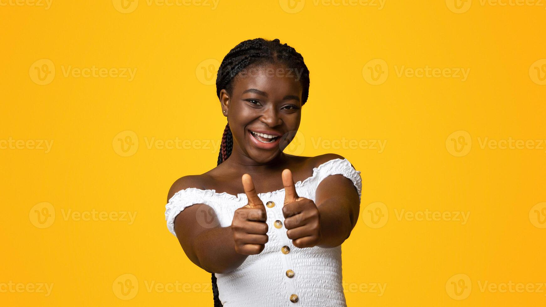 I Like It. Smiling African American Lady Showing Thumbs Up With Both Hands At Camera, Cheerful Black Woman Gesturing Sign Of Approval, Recommending Something, Posing Over Yellow Background, Copy Space photo