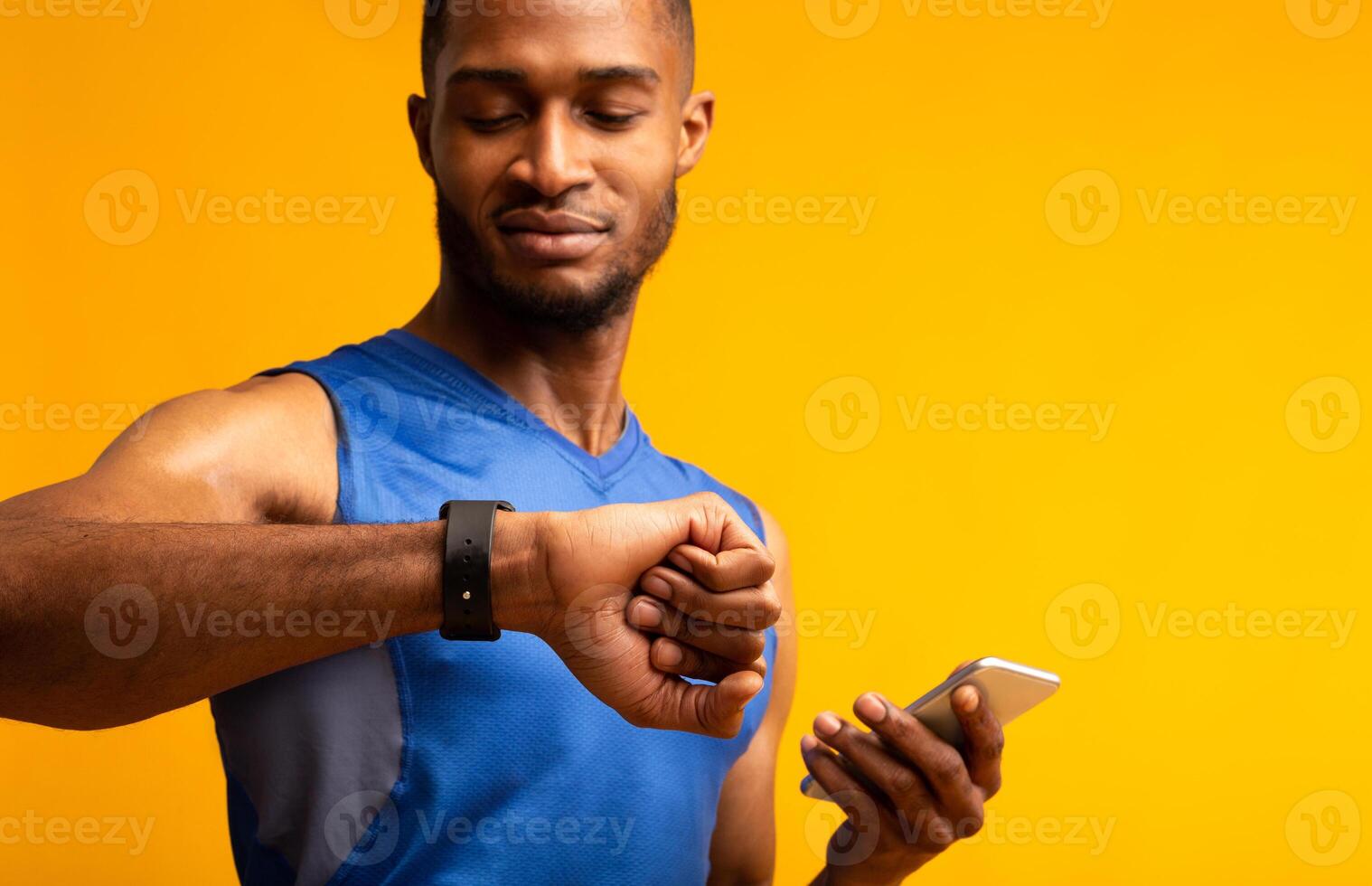 Time To Start. Portrait of black muscular man looking at smartwatch, holding smartphone, checking fitness tracker photo