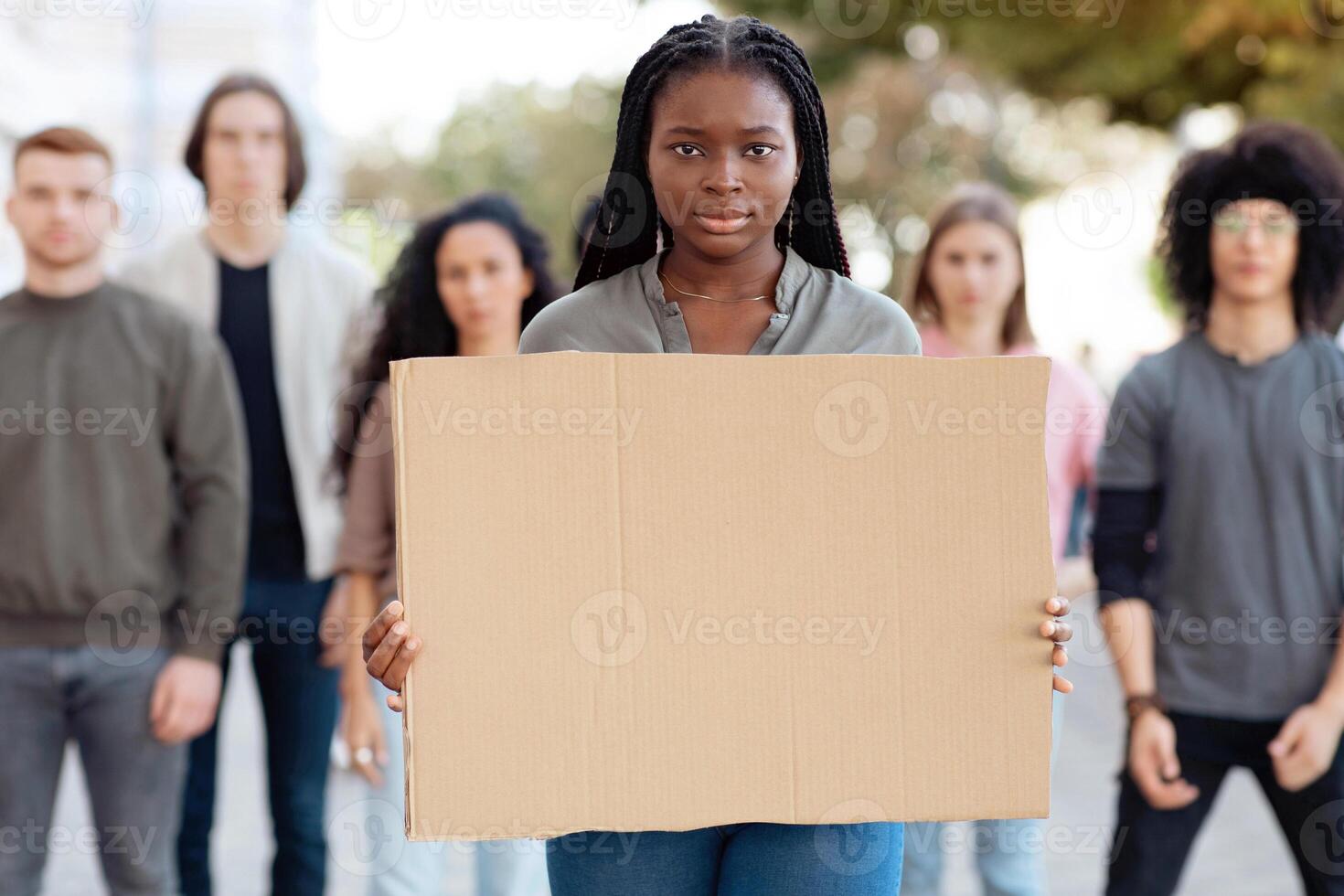 Black woman with empty placard for text and taglines leading group of young multiracial protestors. International group of demonstrators fighting against racism, standing on the street photo