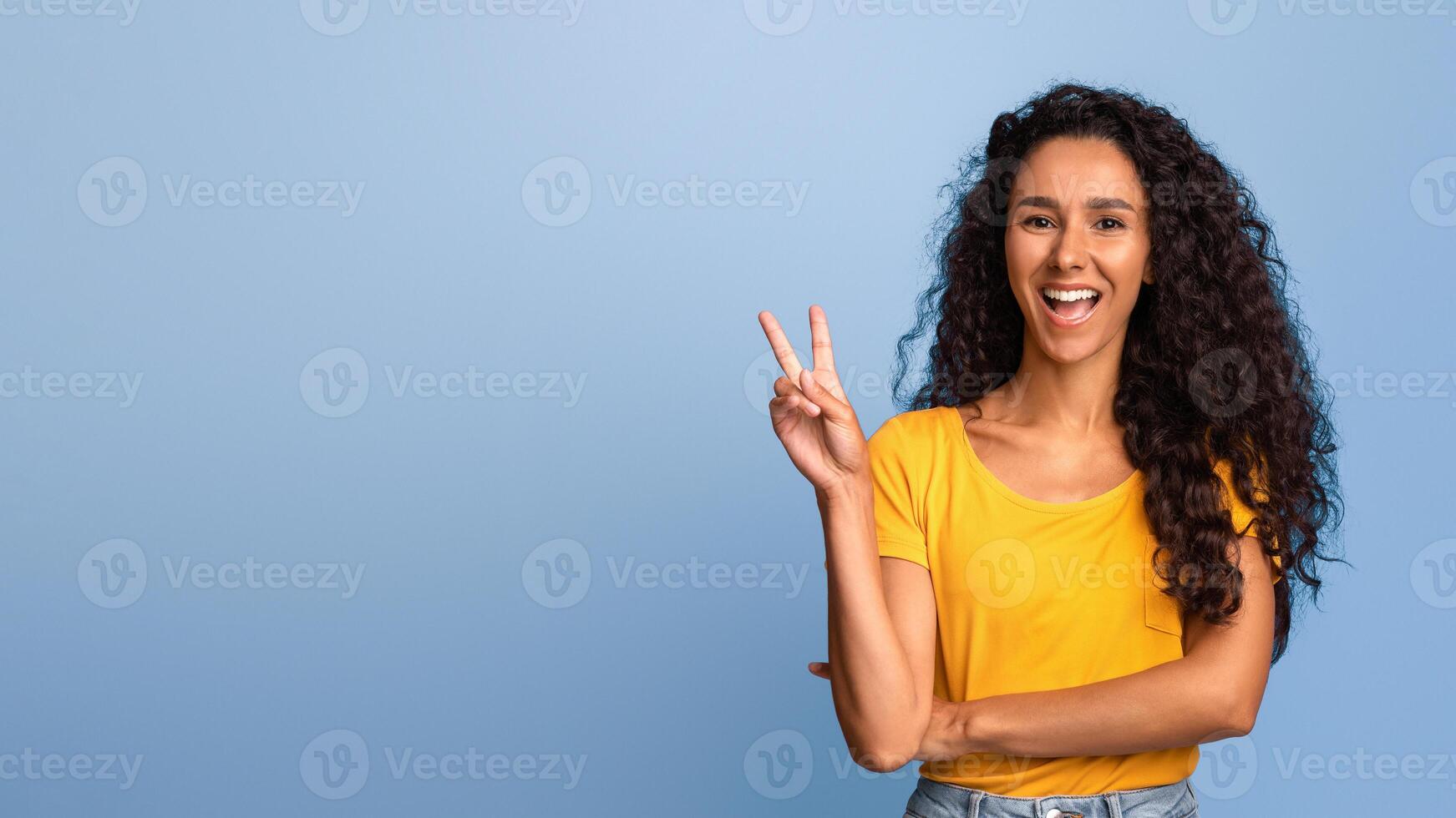 Joyful Young Woman Gesturing Peace While Posing Over Purple Background, Cheerful Brunette Lady Showing V-Sign, Having Fun In Studio, Laughing At Camera, Having Funky Mood, Copy Space photo