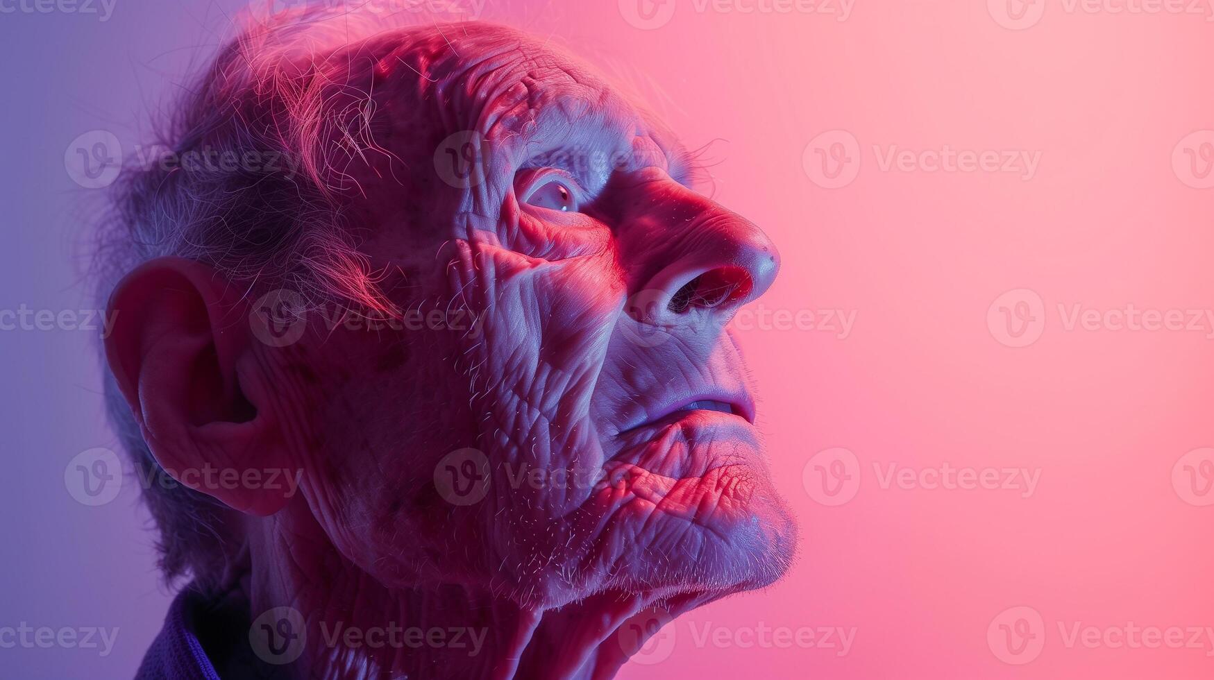This elderly man gazes thoughtfully as colored lights highlight his features, reflecting on aging. photo