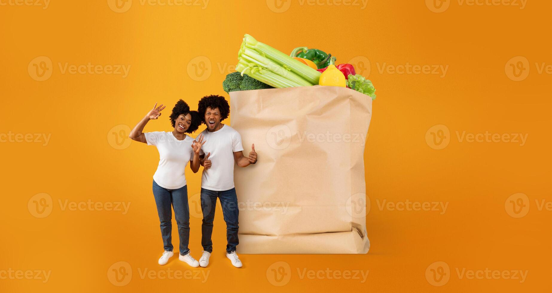 Two joyful customers stand beside a large paper bag filled with fresh fruits and vegetables. This moment captures the excitement of grocery shopping in the current normal. photo