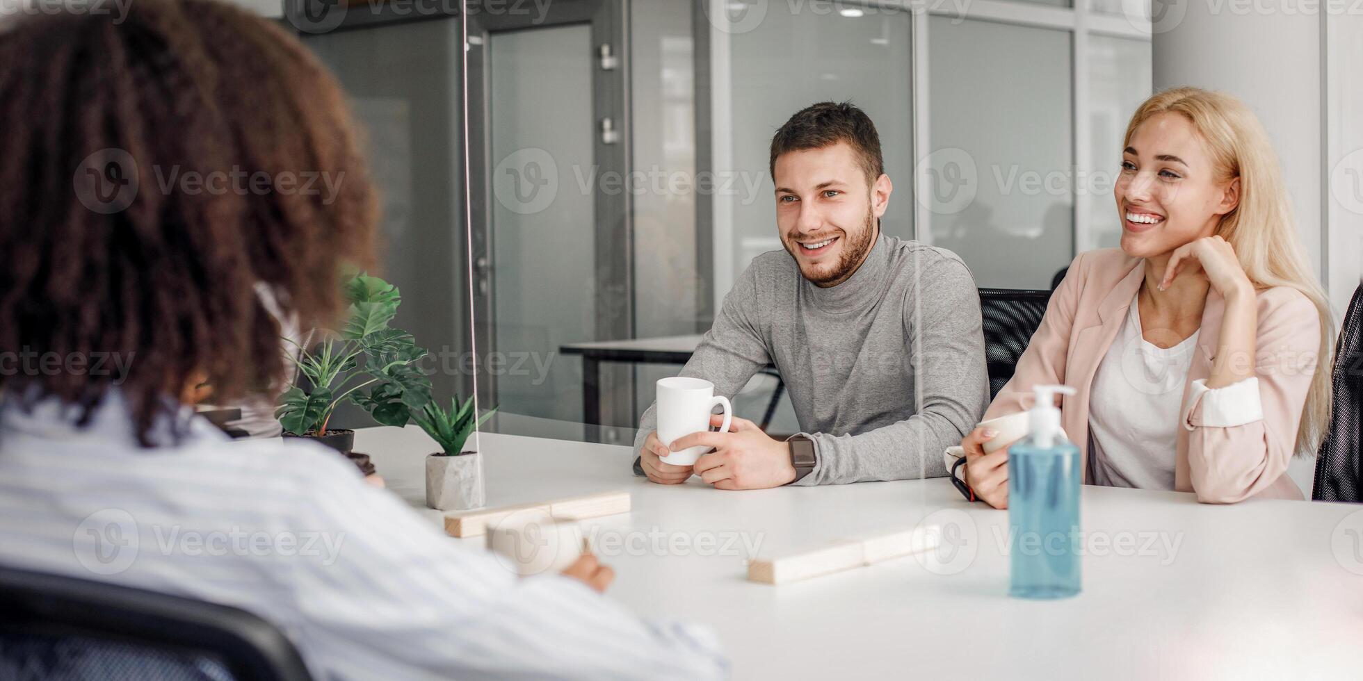 Modern office, coffee break and health protection. Multiracial employees have relax in restroom with antiseptic, cups and protective partition at quarantine, free space photo