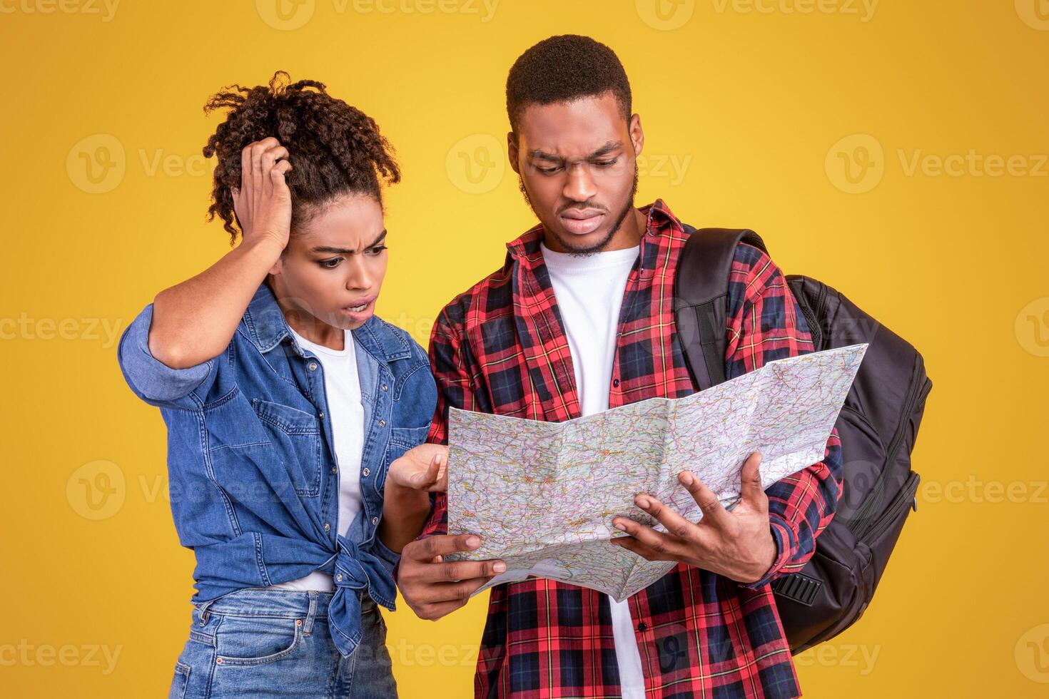 African Tourists Couple Having Problem Planning Vacation Holding Map Choosing Destination Standing Over Yellow Background In Studio. Travel Navigation Problems Concept. Panorama With Copy Space photo