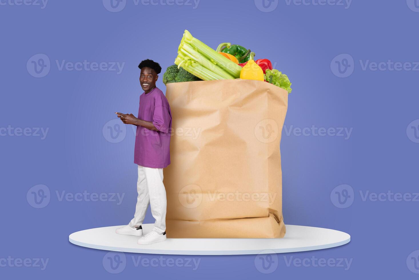 A customer stands near a large paper bag filled with fresh groceries, including vegetables and fruits. They appear to be engaged with their phone, representative of modern shopping habits. photo
