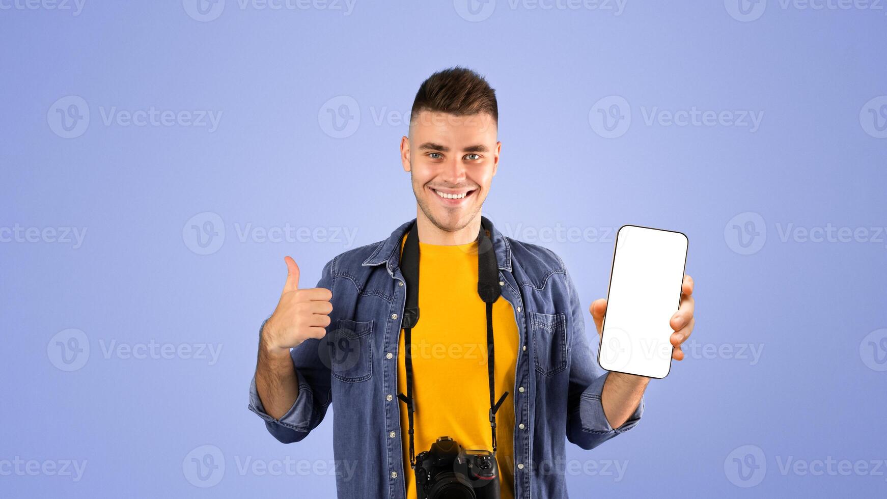 Smiling male traveler with international passport, airplane tickets and professional camera showing thumb up gesture over blue studio background. Spending vacation abroad concept photo