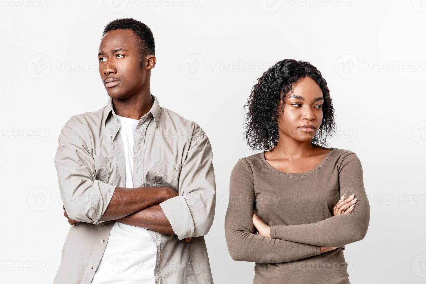 Break up, troubles, misunderstanding in relationships or marriage. Upset african-american man and woman standing next to each other with arms crossed after fight, gray studio background photo