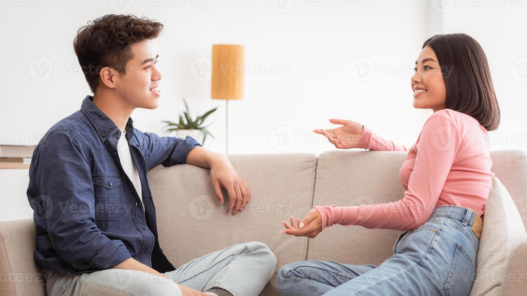 Asian Girlfriend And Boyfriend Talking And Flirting Enjoying Stay-At-Home Date Sitting On Couch At Home On Weekend. Couple's Relationship Communication And Flirt Concept photo