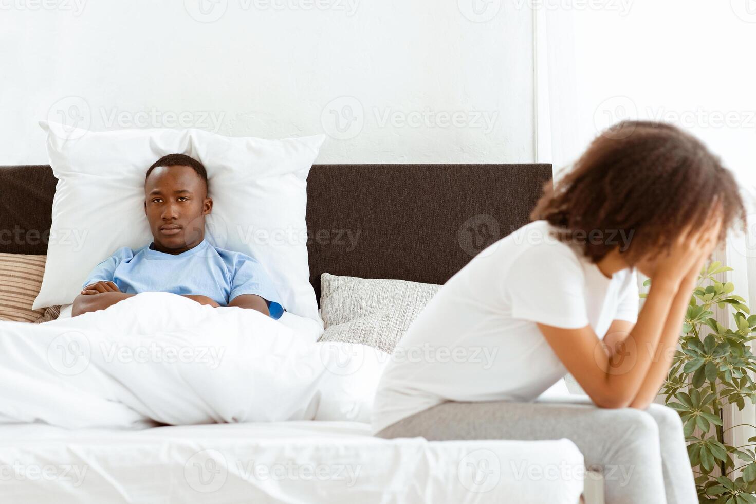 Frustrated lady thinking about relationship problems and cry, thoughtful couple after quarrel, upset lovers consider breaking up. Offended man disappointed with sad african american lady sits on bed photo
