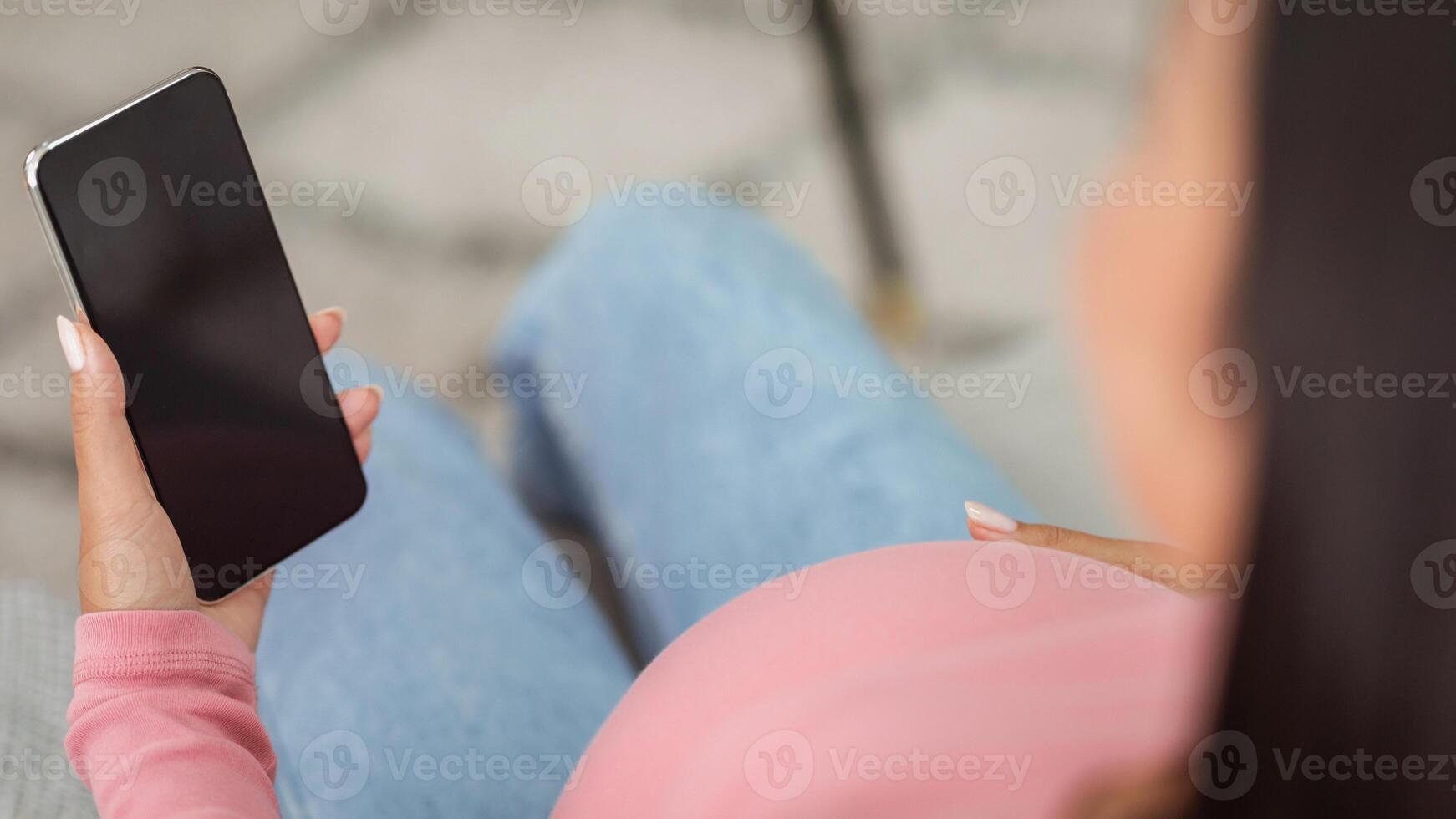 Unrecognizable Pregnant Woman Using Smartphone With Blank Screen Sitting On Couch At Home. Pregnancy Application Concept. Mockup, Cropped, Selective Focus photo