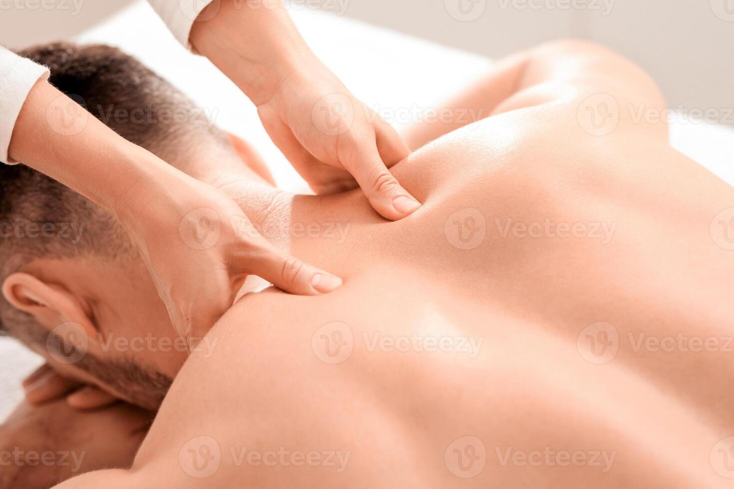 Closeup of man getting acupressure massage at spa salon, top view. Female masseuse massaging unrecognizable man shoulders, pain relief for sportsmen, businessmen and office workers photo