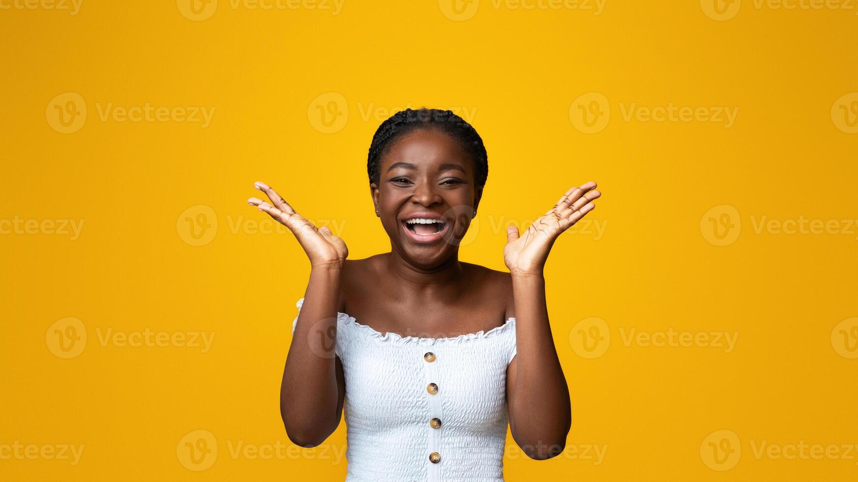 Cheerful African American Woman Laughing And Raising Hands In Excitement, Standing Isolated On Yellow Background, Positive Young Black Lady Emotionally Reacting To Joke, Having Good Mood, Copy Space photo