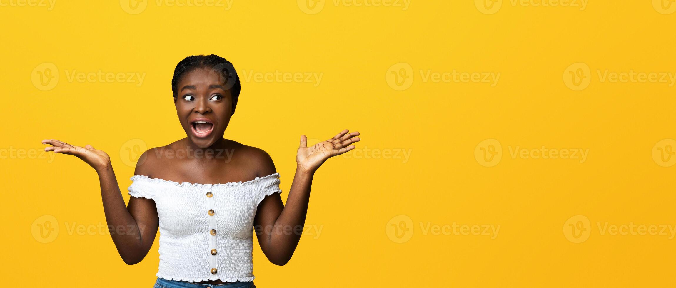 Surprised african american lady spreading hands in excitement and looking at copy space, amazed black lady emotionally reacting to news or offer, standing over yellow background, panorama photo