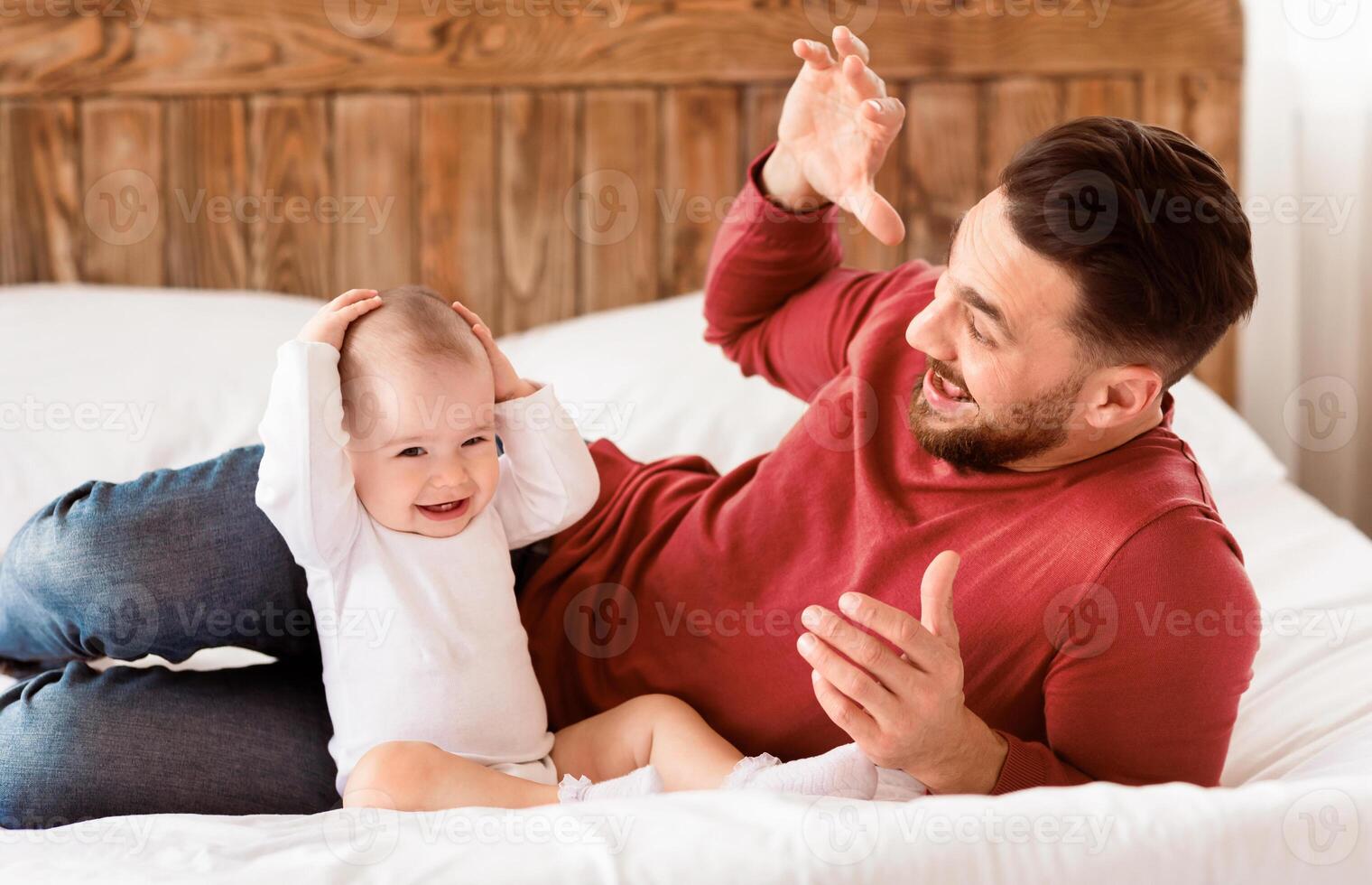 Young Father Playing With Little Baby Daughter Bonding And Spending Time Together Lying On Bed At Home. Loving Dad Having Fun, Plays With Toddler Child. Fatherhood And Parenting Joy Concept photo