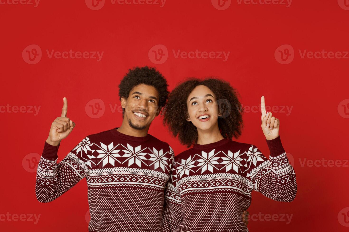 Ideas for modern gifts for family at Christmas, winter holidays and emotions. Happy young african american man and woman show thumbs up and watch to free space, isolated on red background, studio shot photo