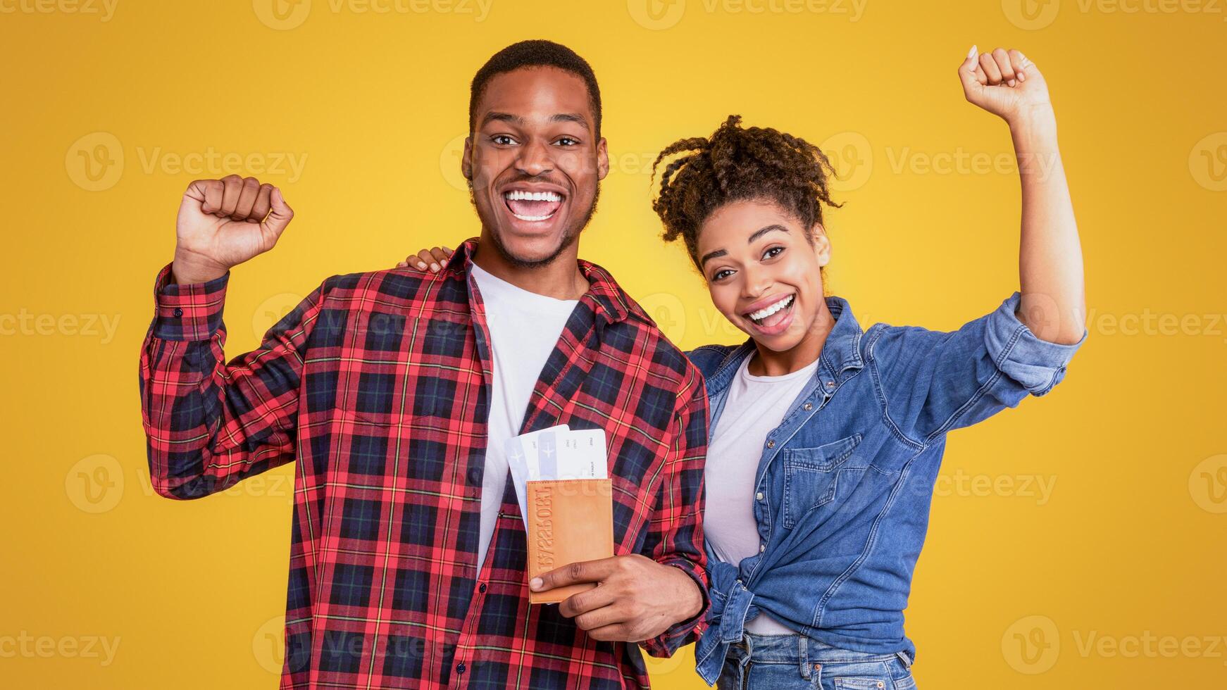 Vacation, Finally. Joyful African American Tourists Couple Holding Flight Tickets Shaking Fists Posing On Yellow Studio Background. Joy Of Traveling, Holiday Trip And Tourism photo