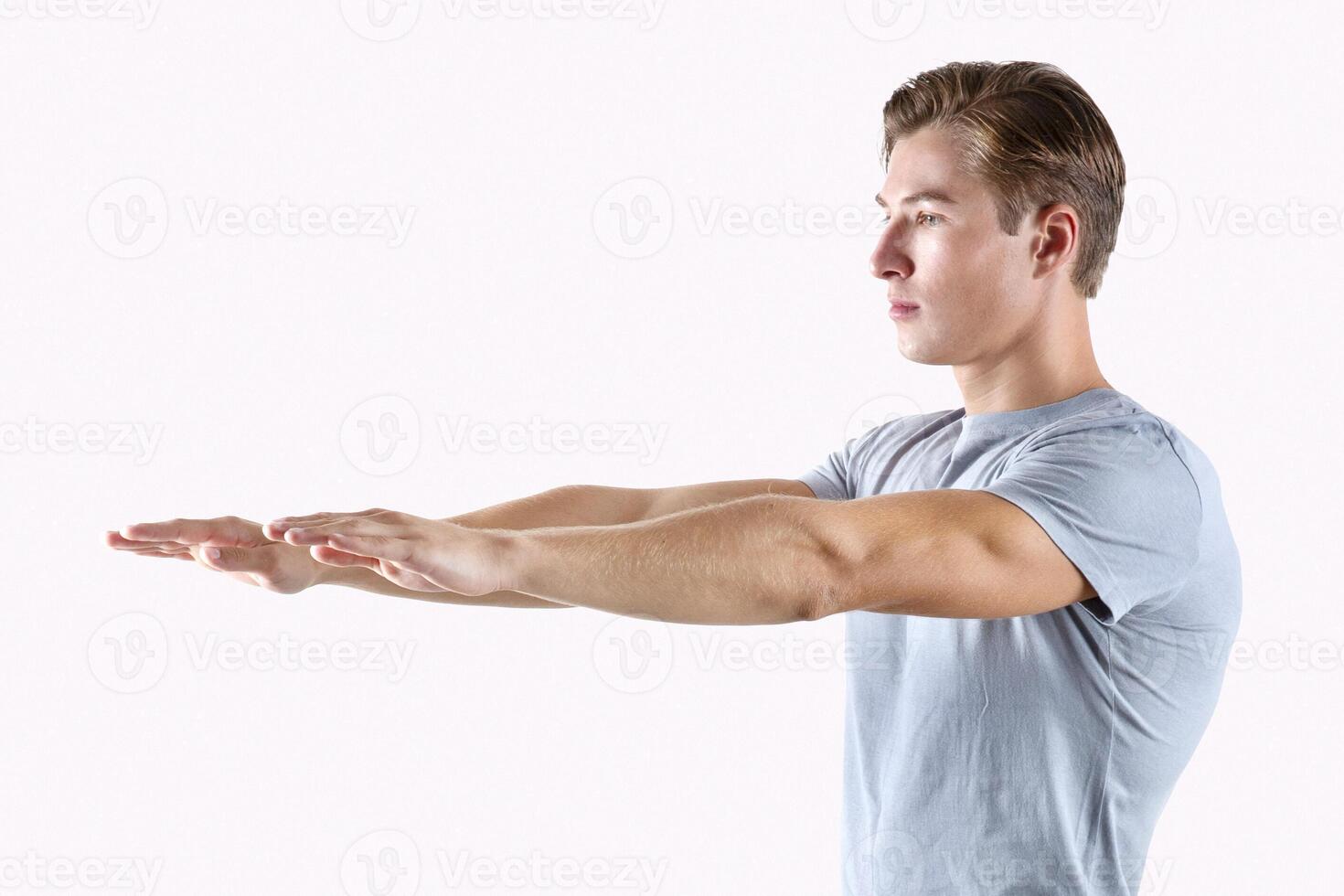 Full length portrait of fit millennial guy in sports clothes doing squats, exercising on light studio background. Determined young athlete warming up for training, promoting active lifestyle photo