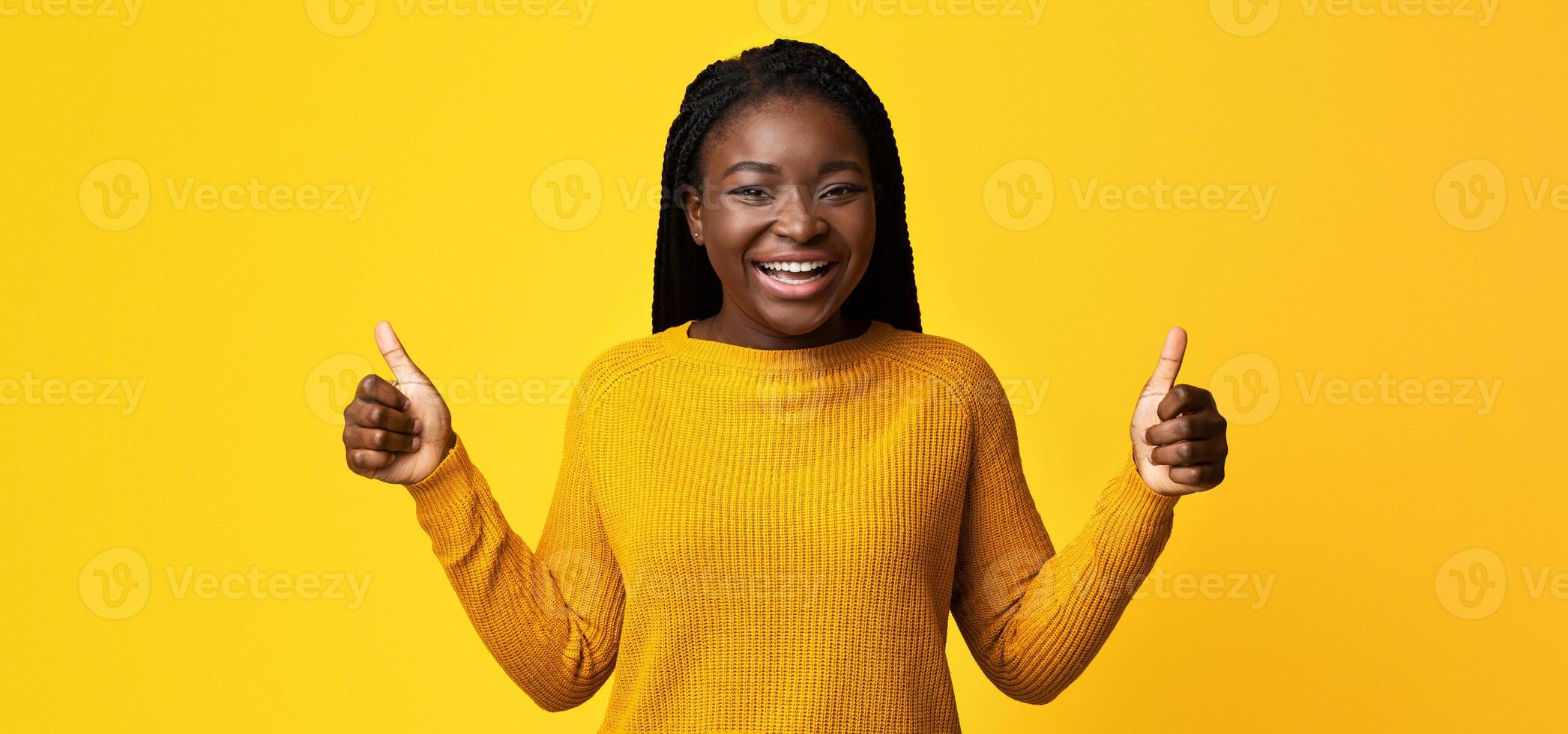 I Like It. Joyful African American Woman In Bright Sweater Showing Thumbs Up At Camera, Positive Black Woman Recommending Something, Gesturing Sign Of Approval, Standing On Yellow Background photo