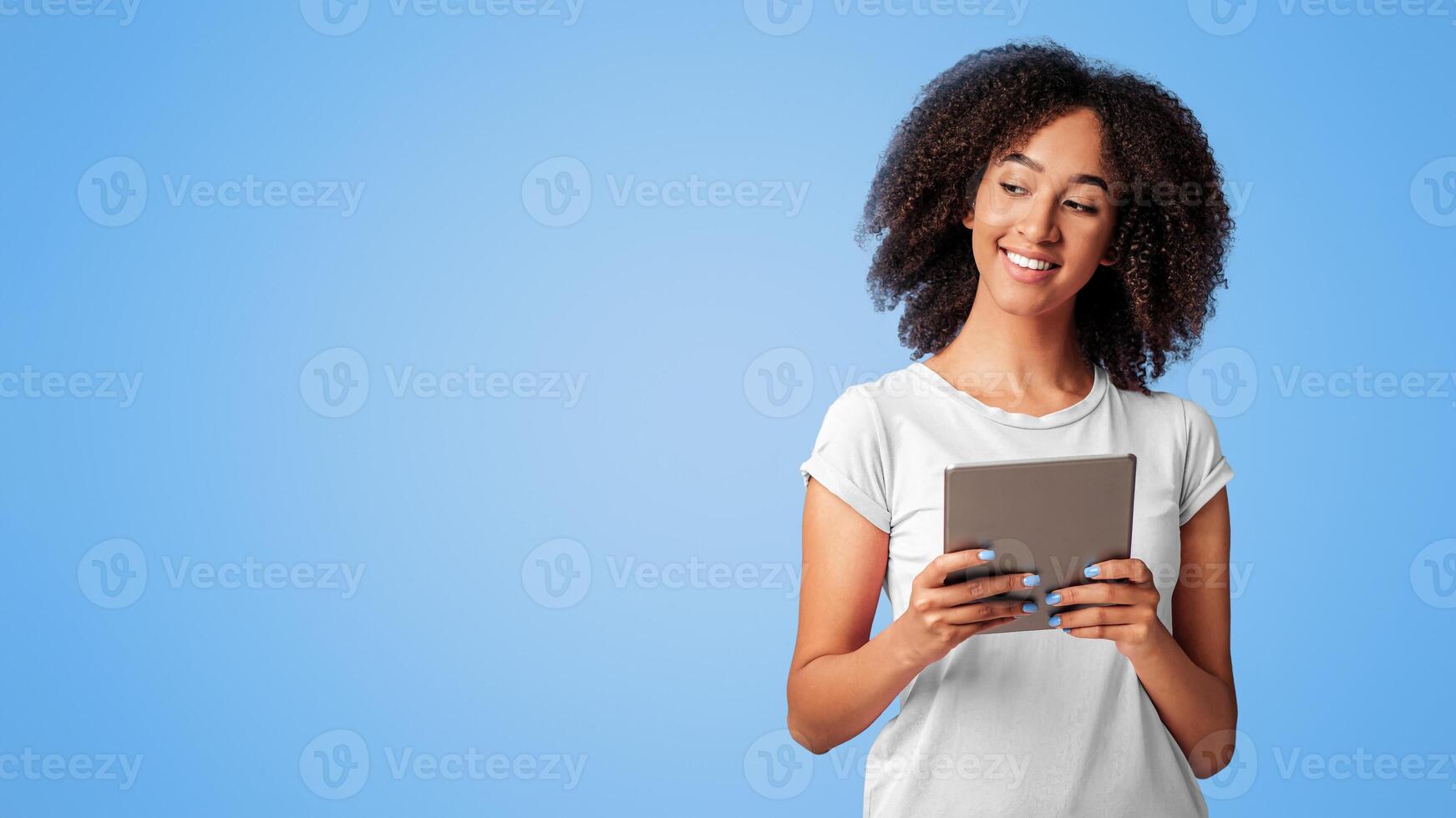 Emotions and feelings, social networks, online work, presentation and good result. Smiling millennial african american woman hold digital tablet and look at free space, isolated on violet background photo