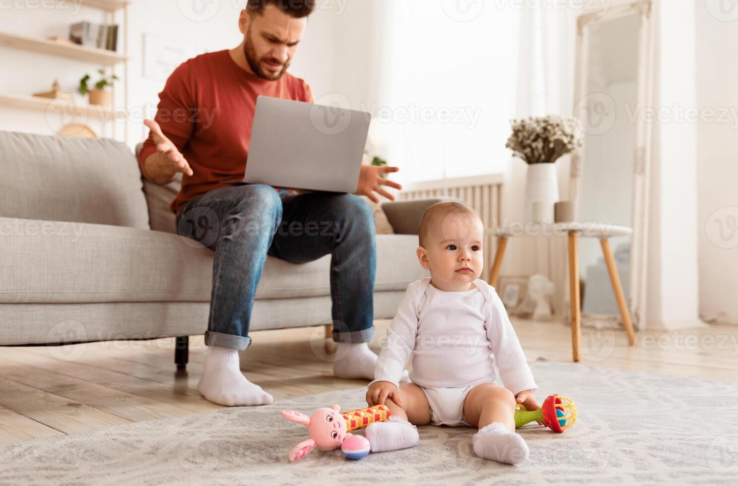 Frustrated Young Father With Baby Toddler Working On Laptop Computer Online, Having Problems At Work Sitting At Home. Paternity Leave And Single Parenting Difficulties. Selective Focus photo