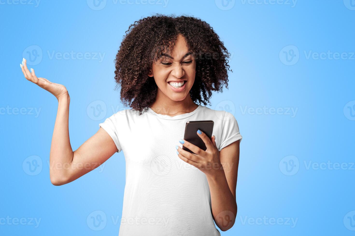 Loss, failed and bad service. Upset millennial african american lady in pink t-shirt with curly hair, reads message and gets angry, isolated on violet background, empty space, studio shot photo