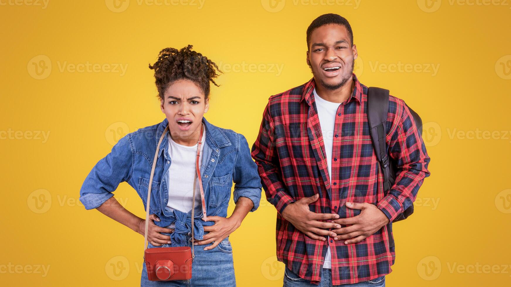 Black Travelers Couple Having Stomachache Suffering From Abdominal Pain After Food Poisoning On Vacation Standing Over Yellow Studio Background. Traveling And Healthcare Problem, Abdomen Ache Concept photo