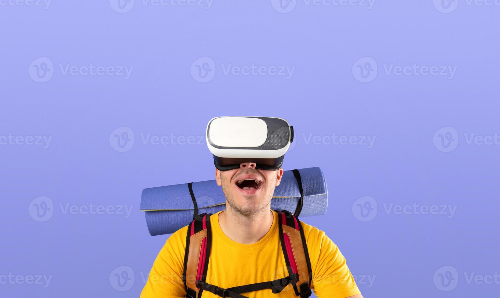 Virtual travel. Happy young man with VR headset and joystick on traveling adventure in cyberspace over blue studio background. Excited guy having tour or journey in augmented reality photo