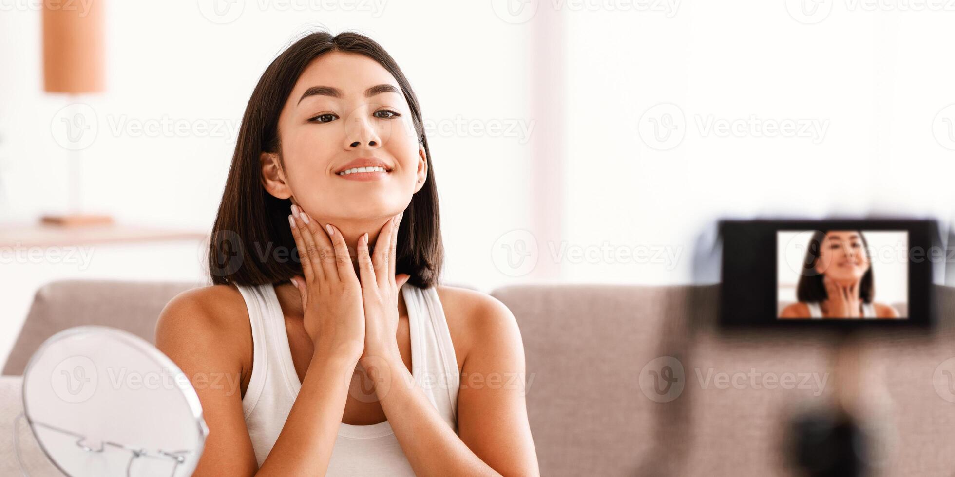 Anti Aging Treatment And Face Lifting. Portrait Of Asian Lady Massaging Her Neck Sitting In Front Of The Camera, Recording Vlog For Her Internet Channel At Social Media. Blogger Showing Facial Massage photo