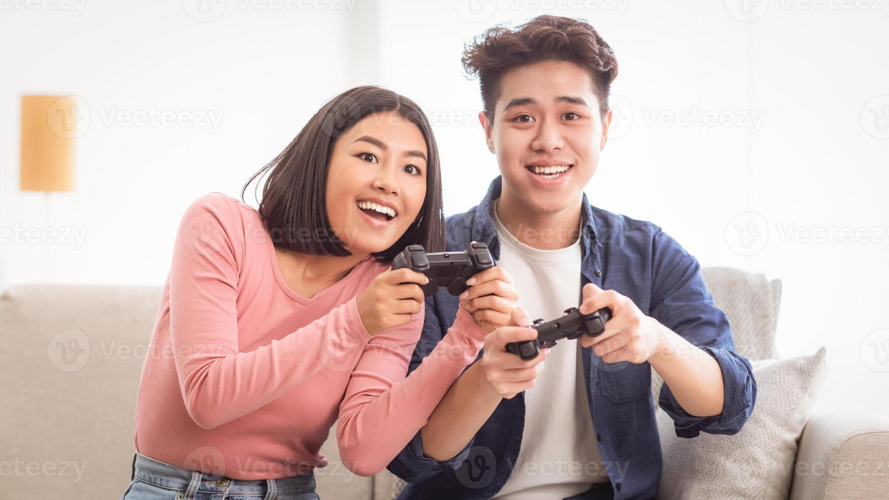 Cheerful Asian Couple Playing Game Together Having Fun Sitting On Couch At Home. Videogames For Family Of Two, Computer Gaming Hobby And Domestic Weekend Leisure Concept photo