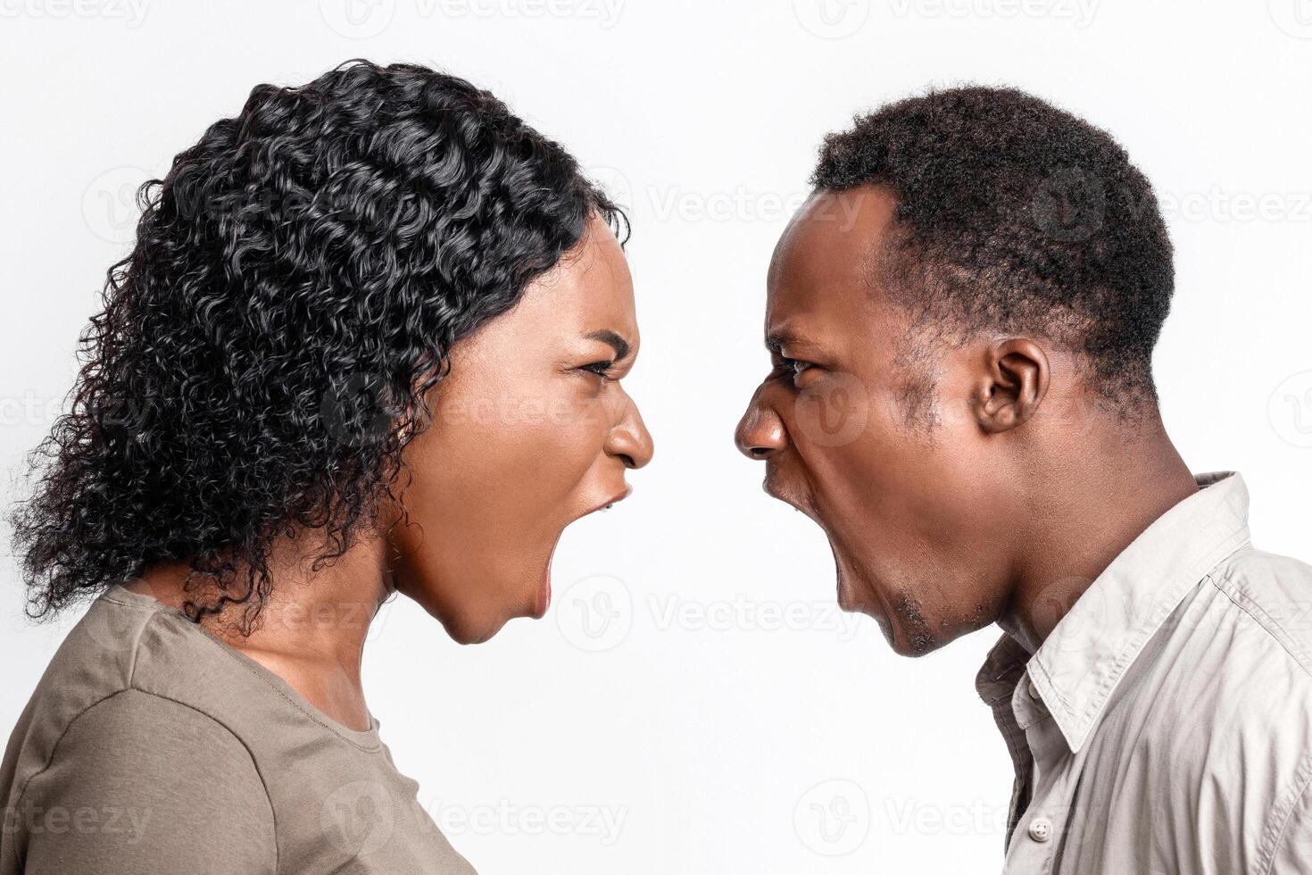 Fight during isolation. Black man and woman shouting at each other over grey studio background. Closeup of african american couple fighting, looking at each other and yelling, profile view photo