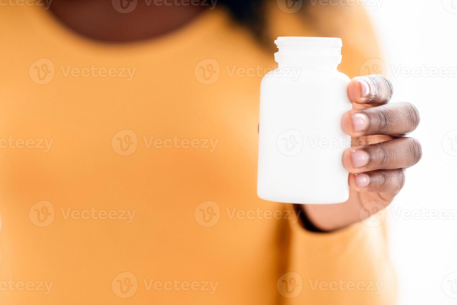 Closeup of black pregnant woman holding jar with pills or vitamins. Unrecognizable african american expecting lady recommending supplements for future mothers, selective focus on vitamins photo