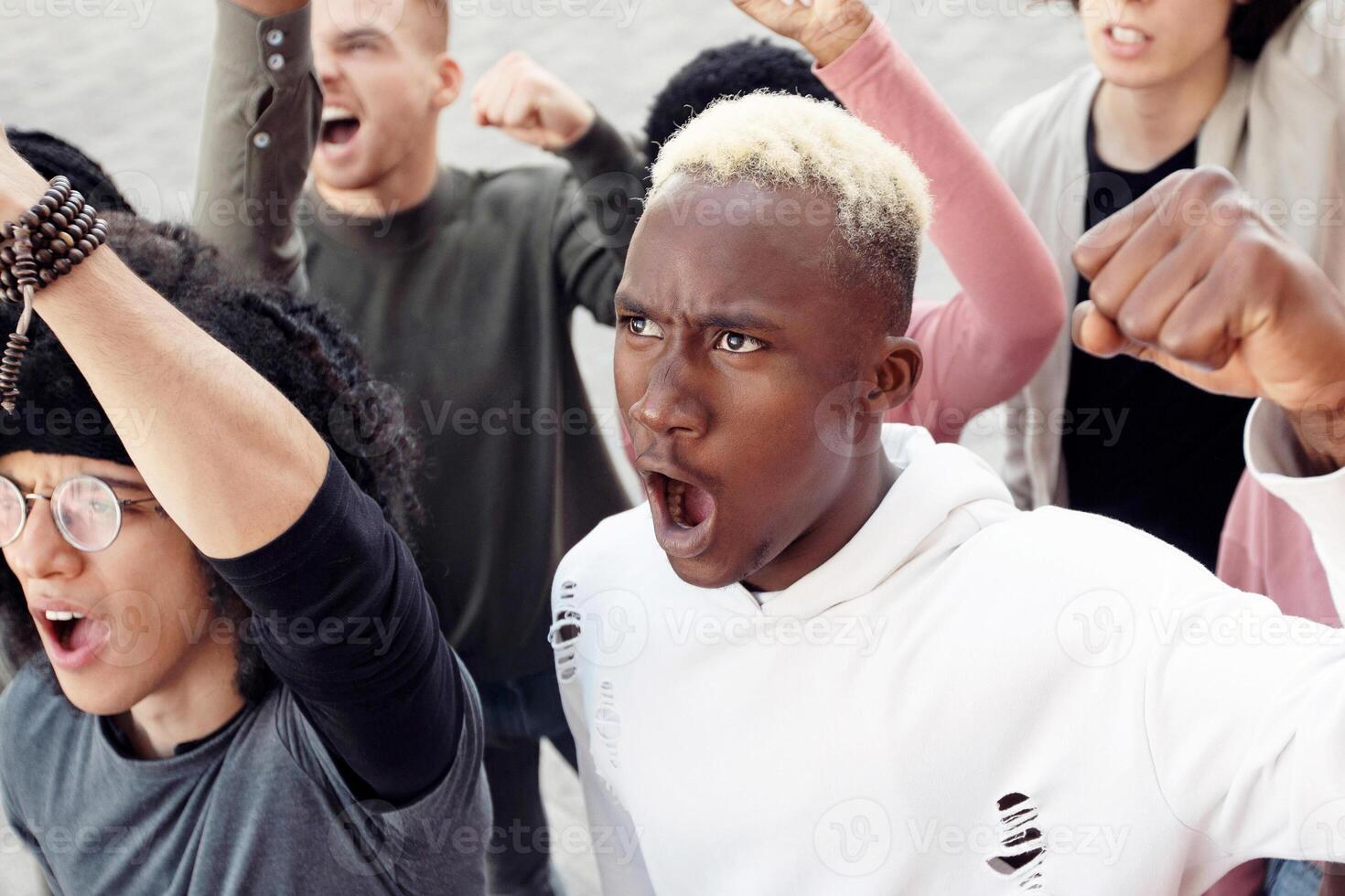 Multiethnic protestors striking against reforms on the street, closeup. International group of young people making riot next to government building, top view. Racism, discrimination concept photo