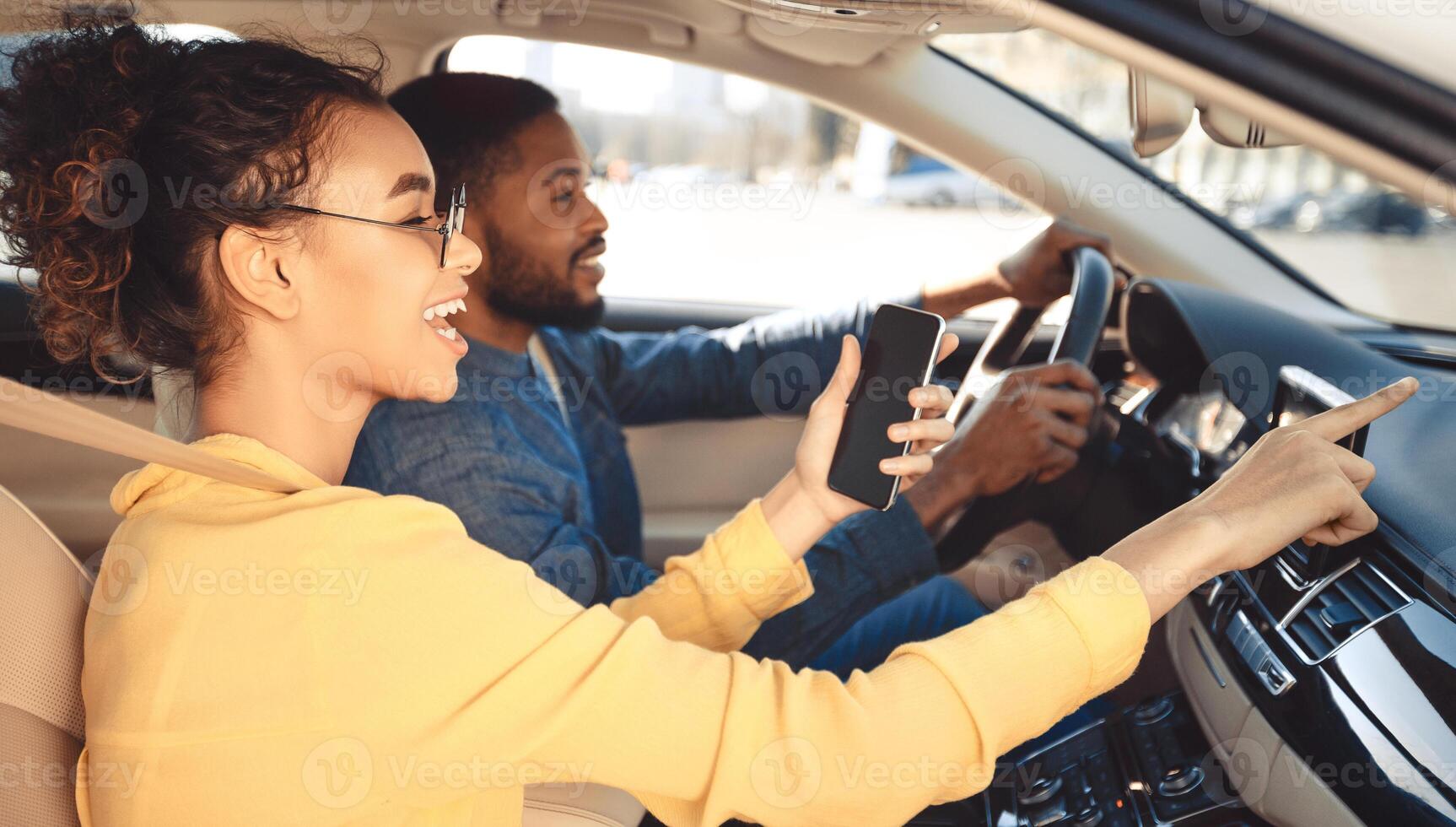 Afro couple driving car and using gps navigator on mobile phone, driving to new destination photo