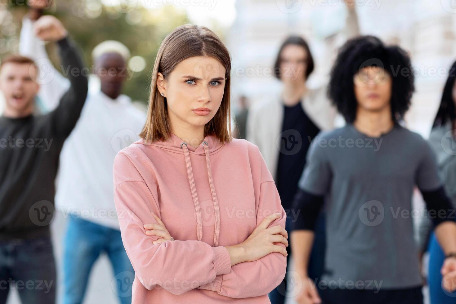 Selective focus on angry young lady posing over multiracial group of activists, strikers different nationalities walking by street, protesting against discrimination, fighting for human rights photo