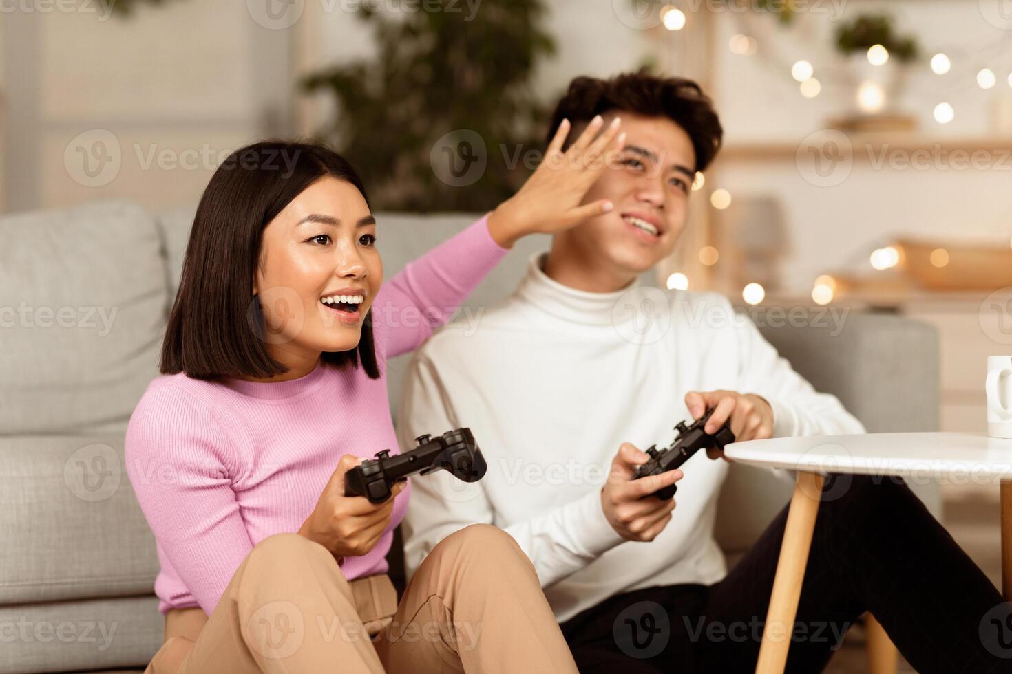 Japanese Spouses Playing Computer Games Having Fun Sitting On Couch At Home. Asian Girlfriend Winning Videogame Spending Weekend With Boyfriend. Games And Gaming Concept. photo
