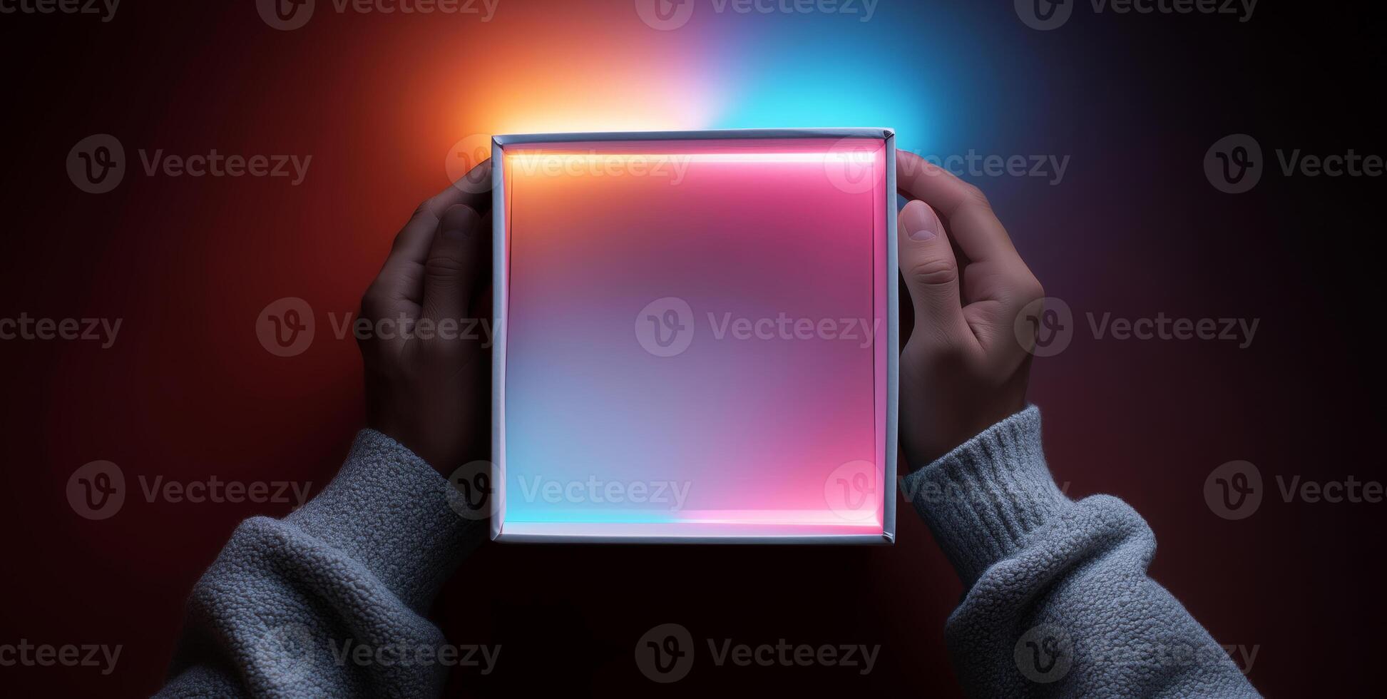 A person holds an open delivery box with vibrant inner illumination. The soft glow creates a contrasting effect against the dark background. photo
