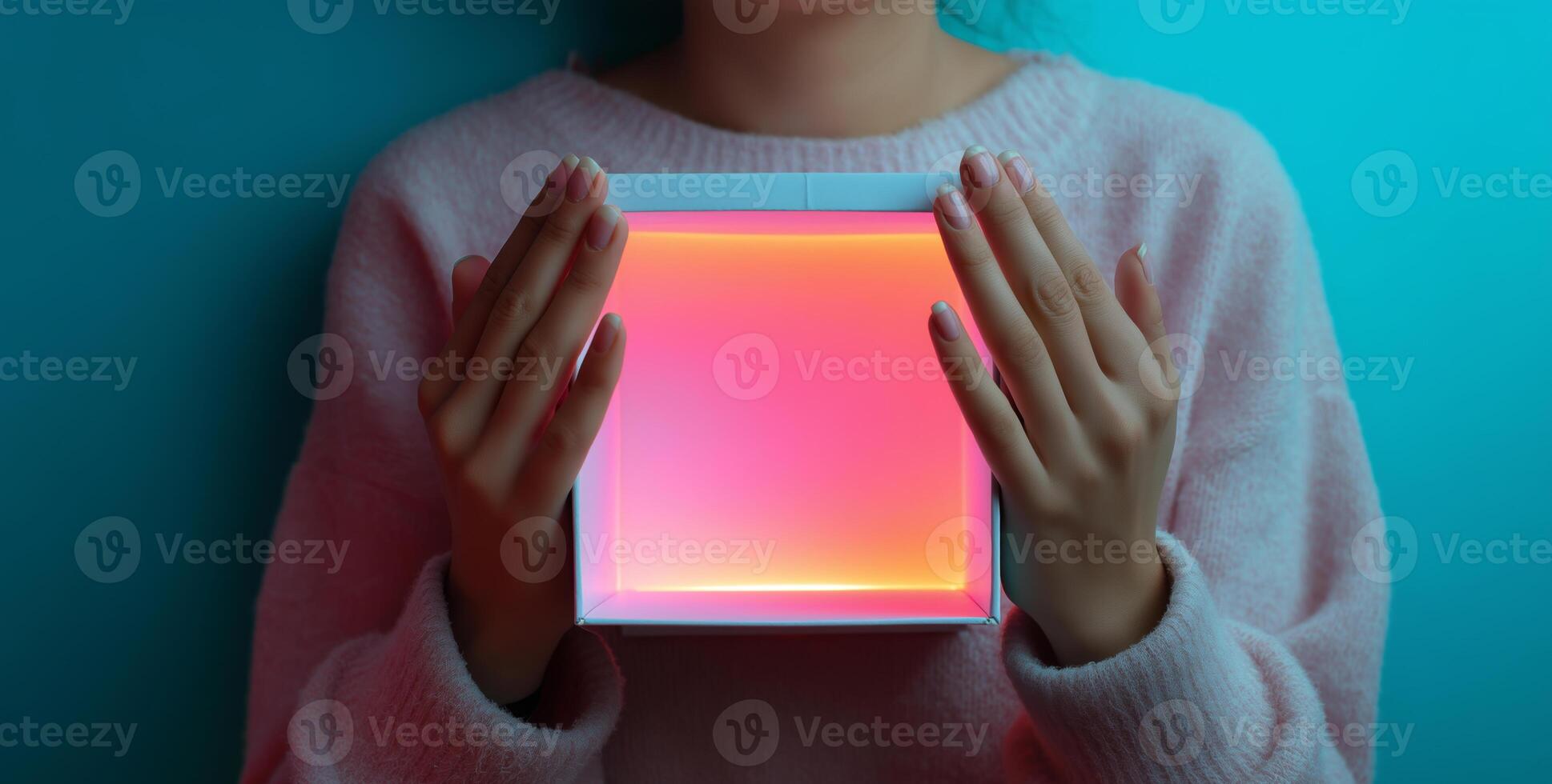 A person gently holds an open box that emits bright colors, creating an eye-catching display. The setting features a calming blue background, enhancing the visual appeal. photo