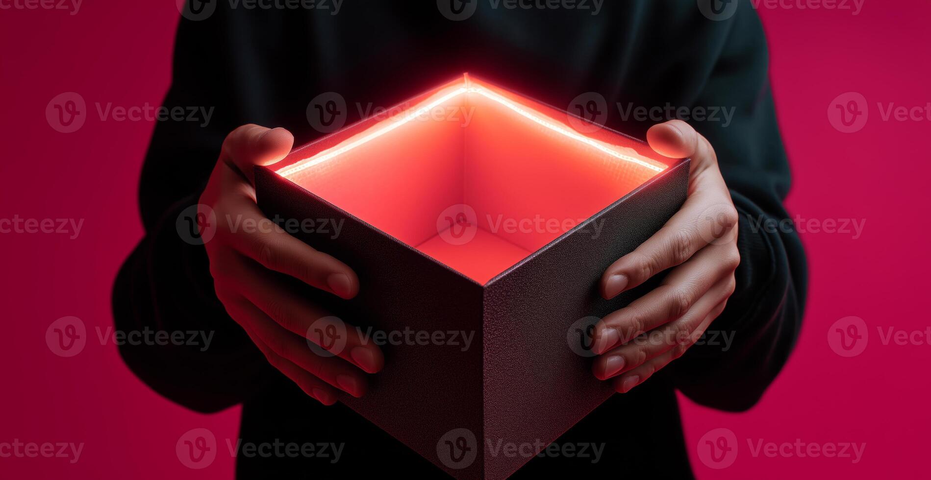 Hands hold an open delivery box with a glowing red interior against a vibrant background. The moment captures curiosity and anticipation as the contents remain unseen. photo