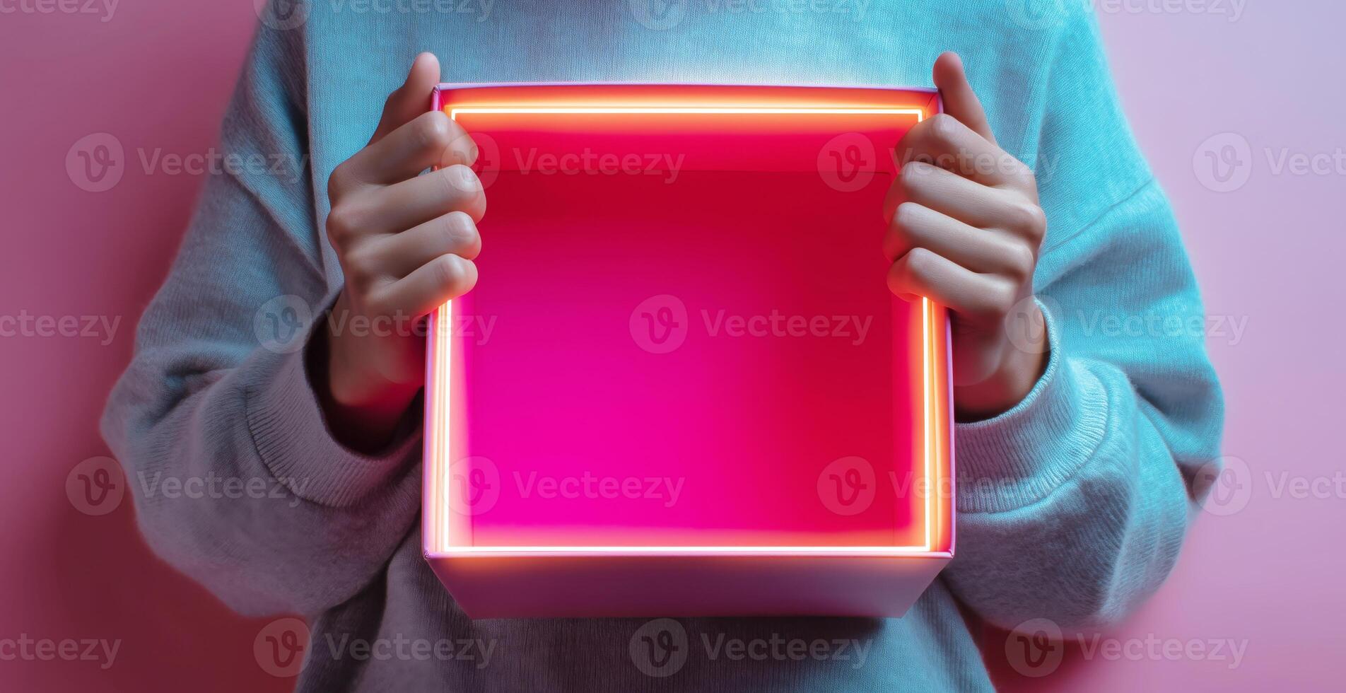 A person is holding an open box, showcasing its bright inner lining. The scene features a warm pink background, creating a lively atmosphere. photo