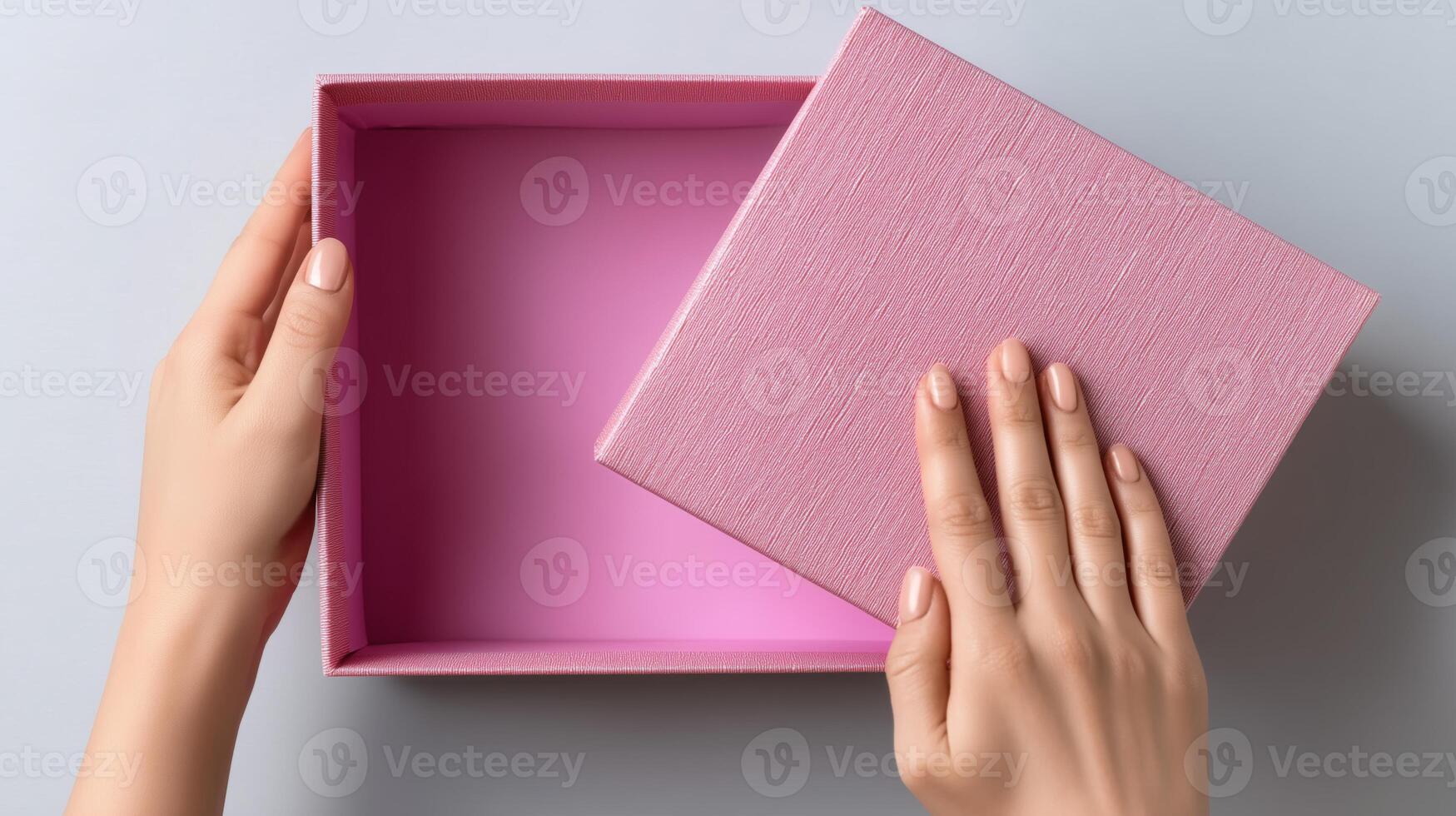 Hands grasp a pink delivery box, lifting the lid to reveal an empty interior. The setting is bright and minimalistic, showcasing the anticipation of discovering its contents. photo