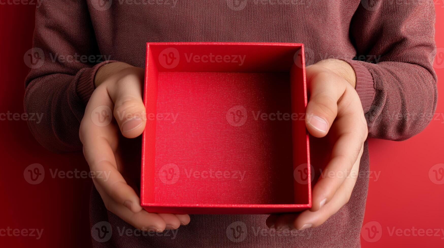 A pair of hands presents an open red box, suggesting a delivery parcel just received. The box is empty, contrasting with the solid red background, emphasizing anticipation and mystery. photo