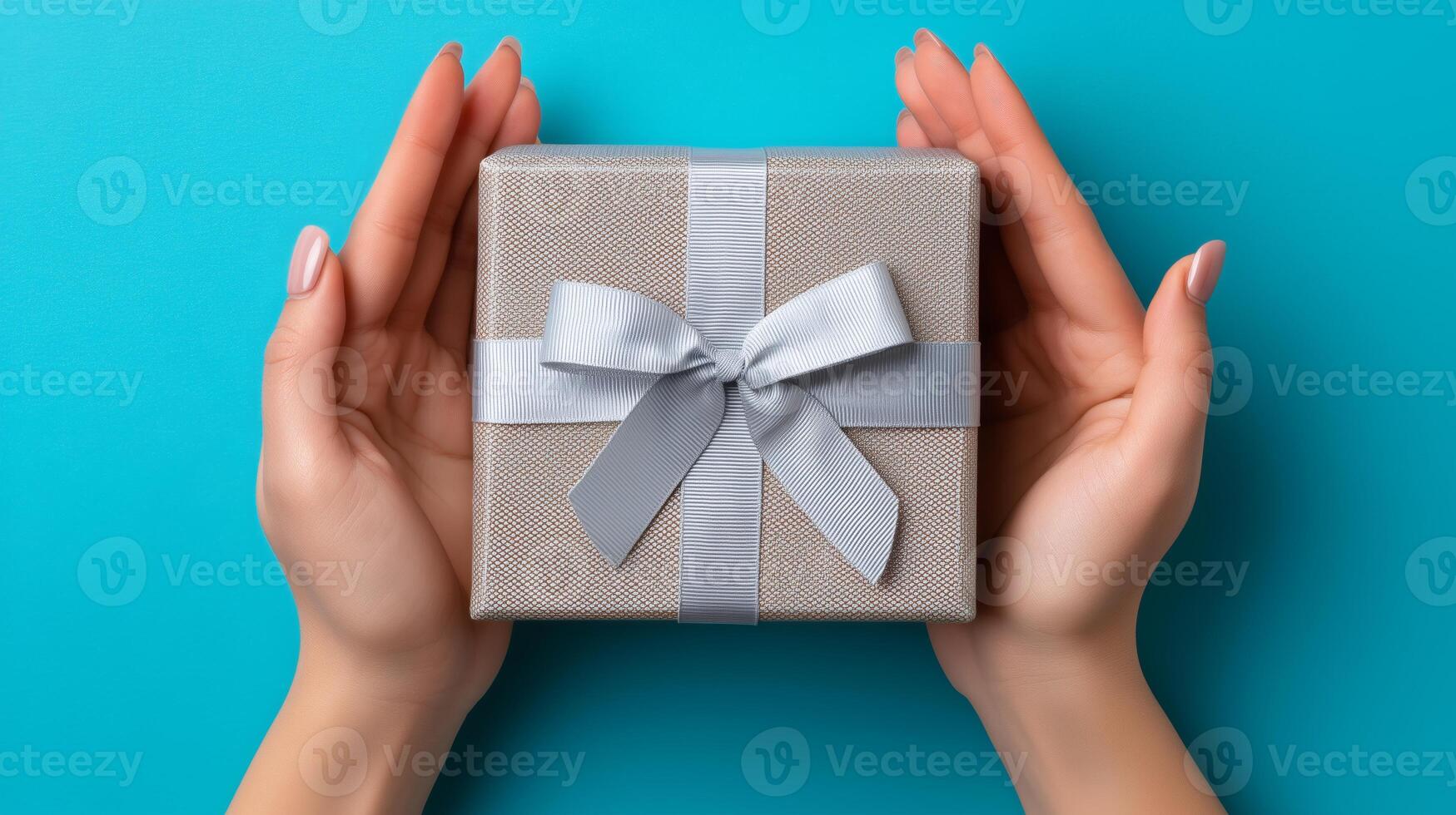 Two hands gently cradle an open delivery box adorned with a silver ribbon against a bright turquoise background. The box appears ready for gifting or reveal, suggesting excitement and anticipation. photo