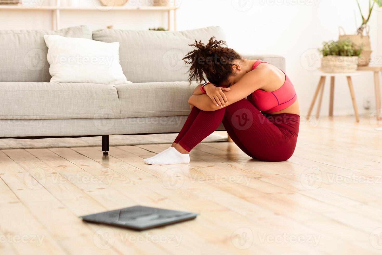 Weight Loss Failure. Unhappy African American Lady Crying Sitting Near Scales After Weighing Herself And Gaining Kilograms At Home. Excess Weight Problem Concept. Selective Focus, Shallow Depth photo