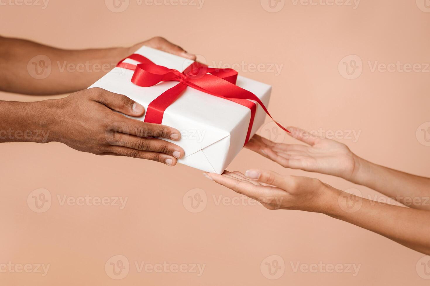 Happy New Year celebration holiday on party. Hands of african american man give box with gift in wrapped to woman, congratulating wife isolated on light background, close up, cropped, studio shot photo