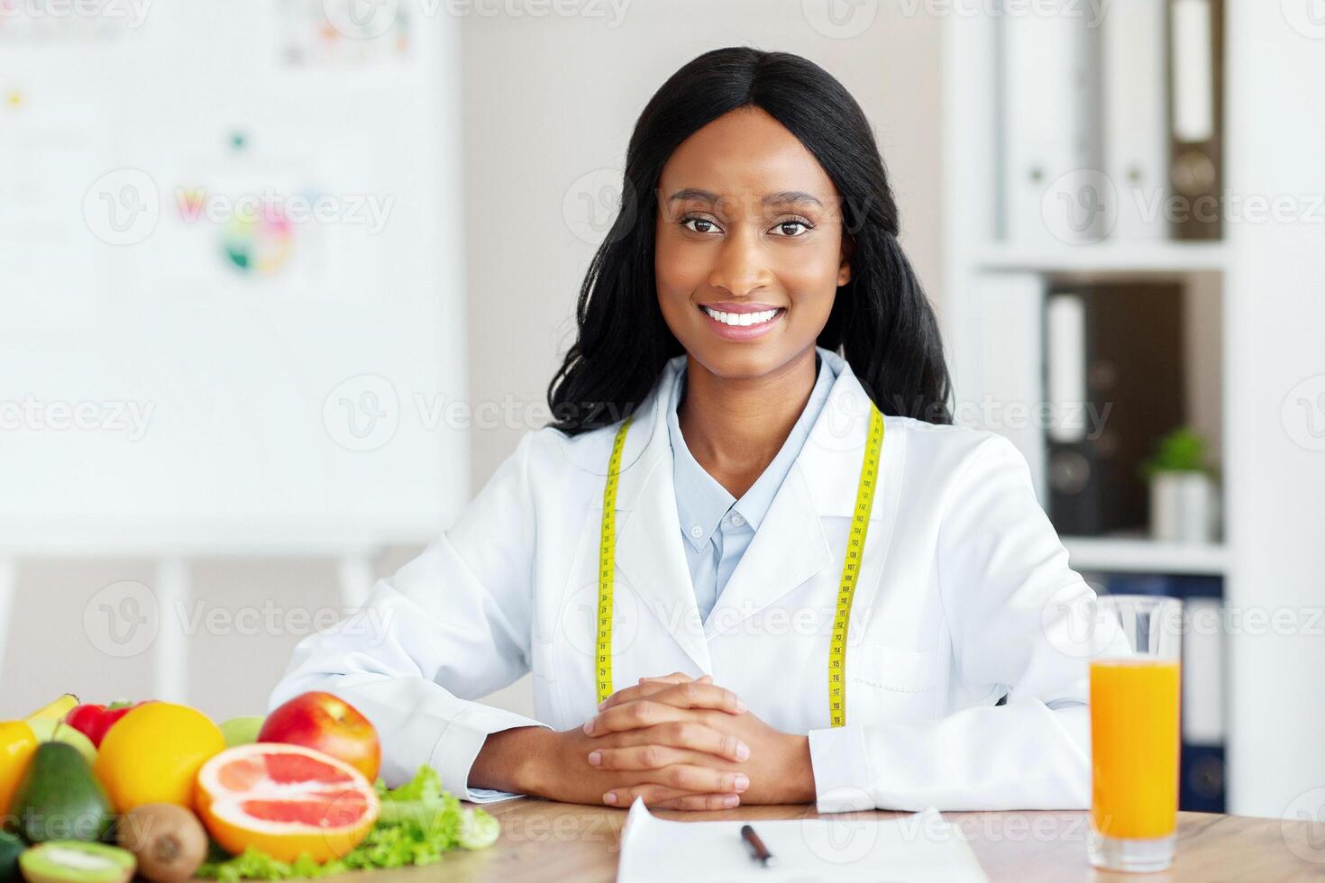 Portrait of young black weight loss consultant smiling at camera in modern clinic, space for text. African American female dietitian recommending plant based healthy meal plan photo