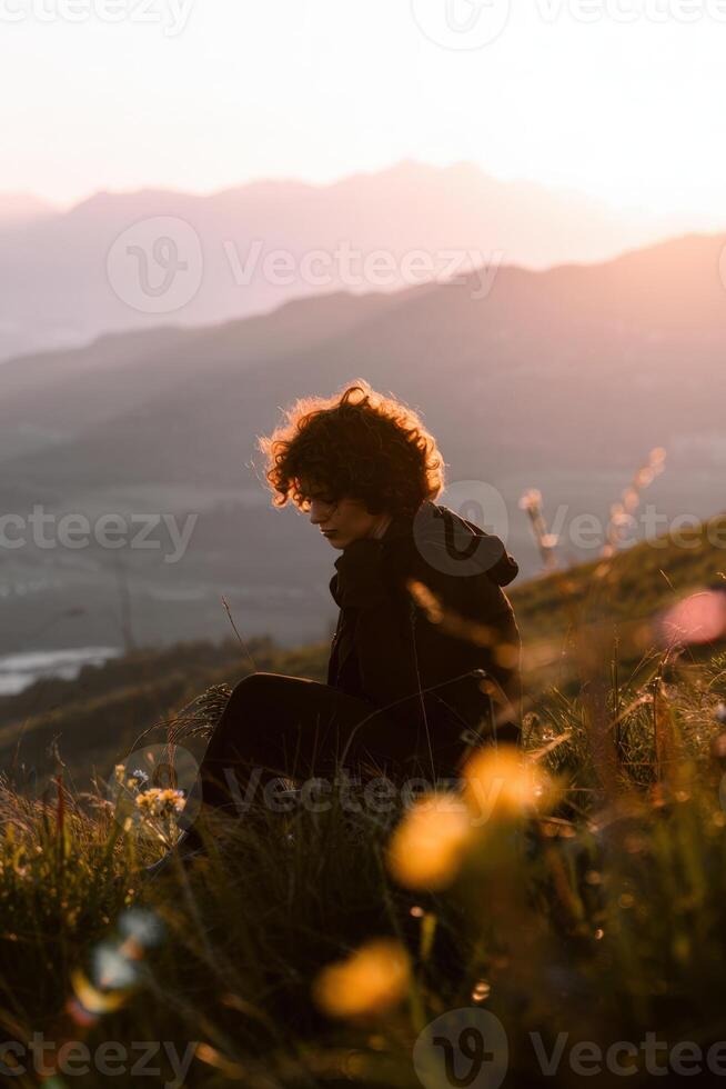 Young Person Contemplating in Grass Field at Sunset photo