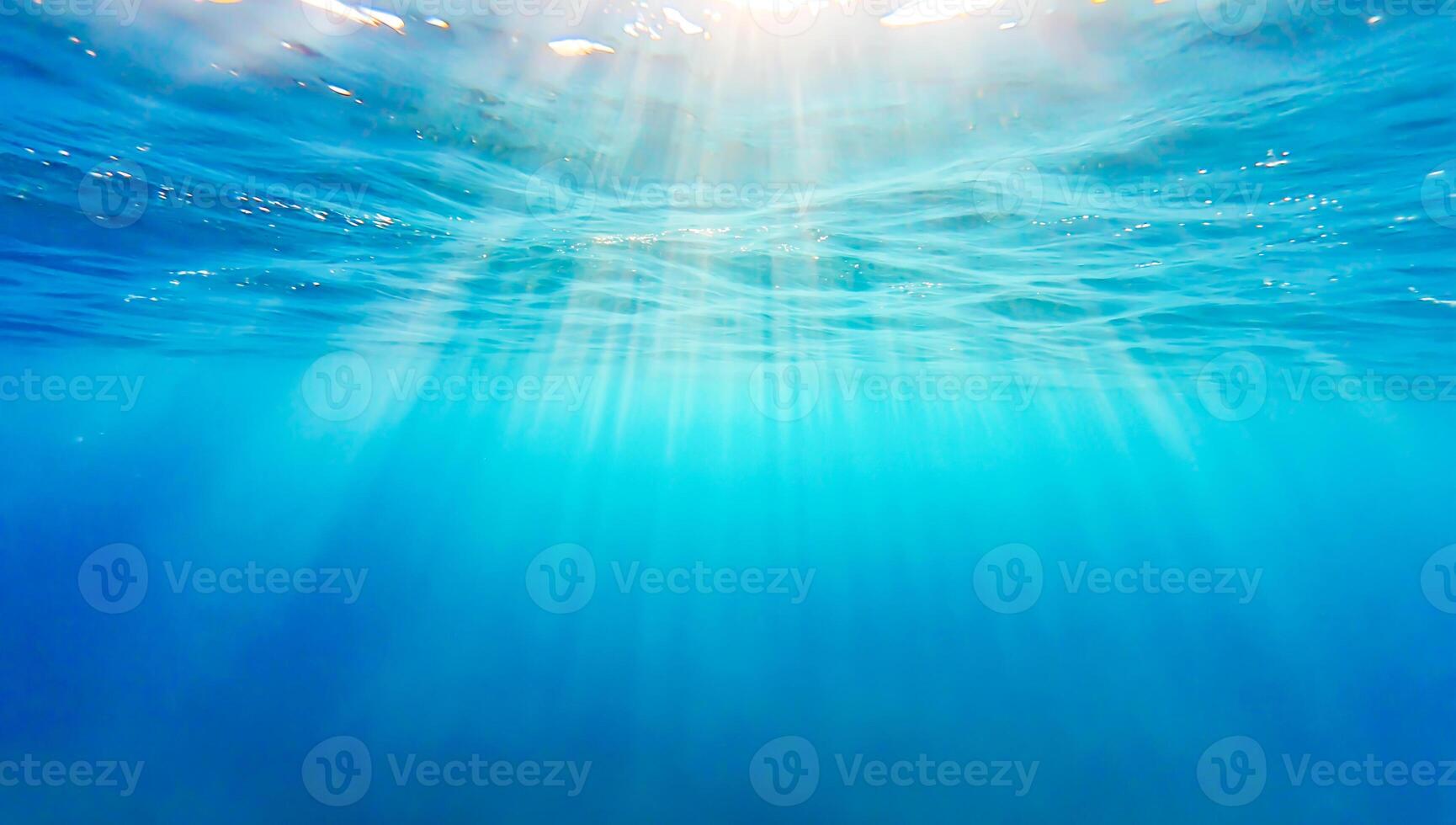 Sunlight beams penetrating the crystal-clear blue ocean, creating serene underwater atmosphere. Concept of nature backgrounds, ocean depth, marine beauty, travel, diving, and peaceful nature photo